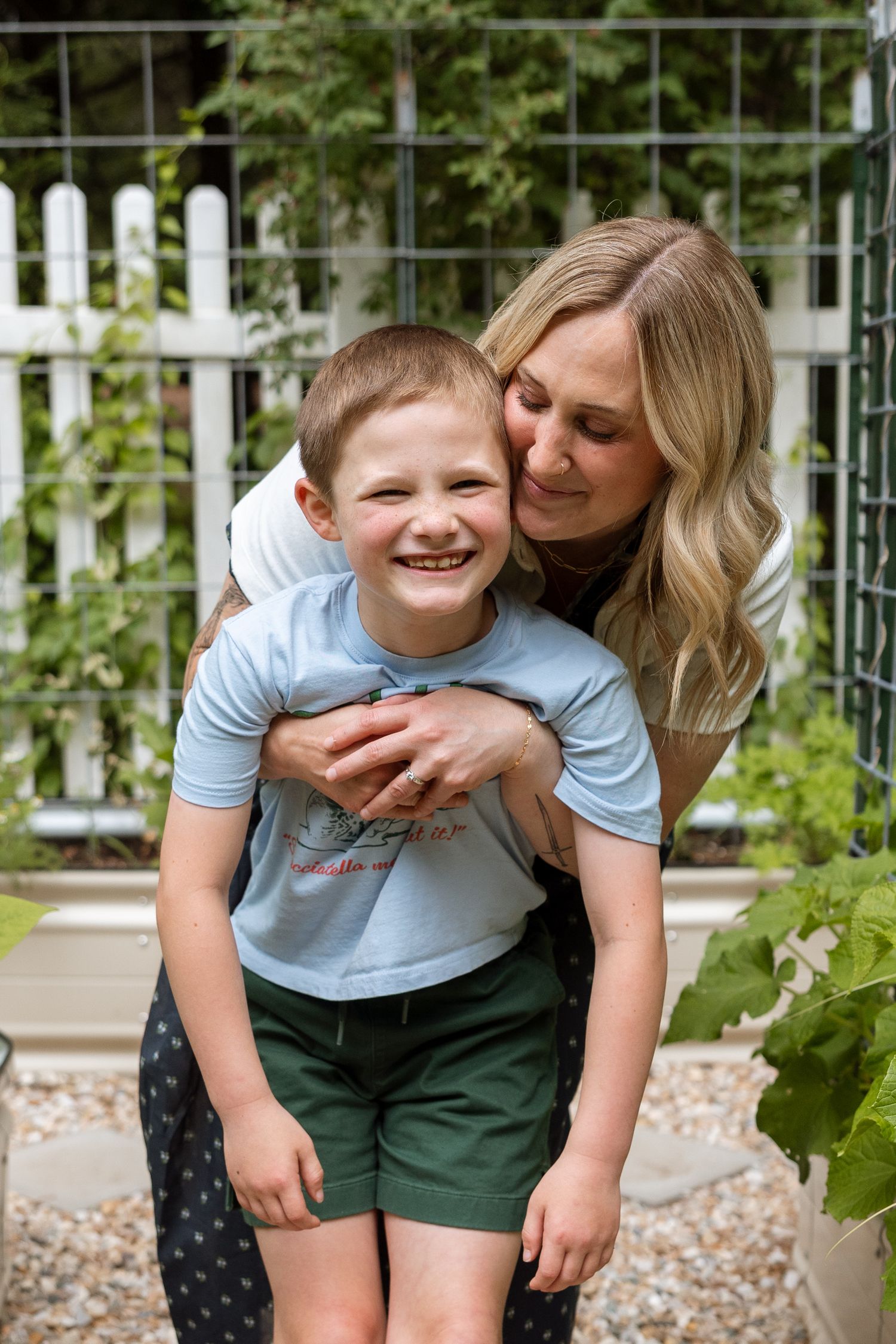 A heartwarming moment of affection and laughter shared between parent and child in a garden setting.