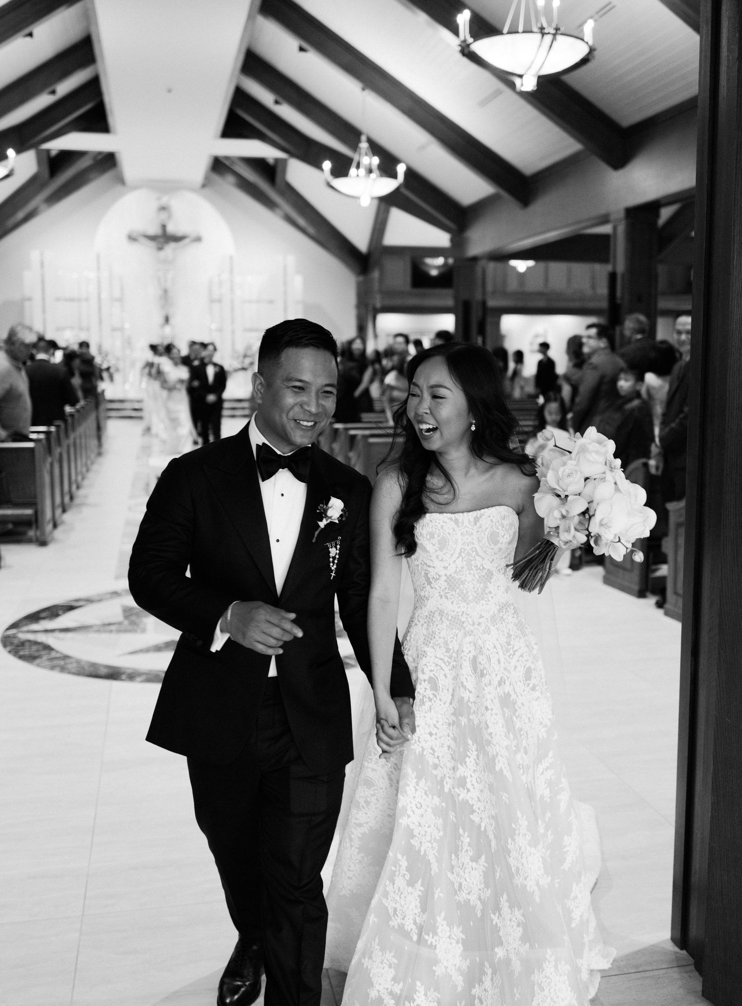 A wedding celebration in black and white showing joyful moments between a couple in formal attire at an indoor venue.