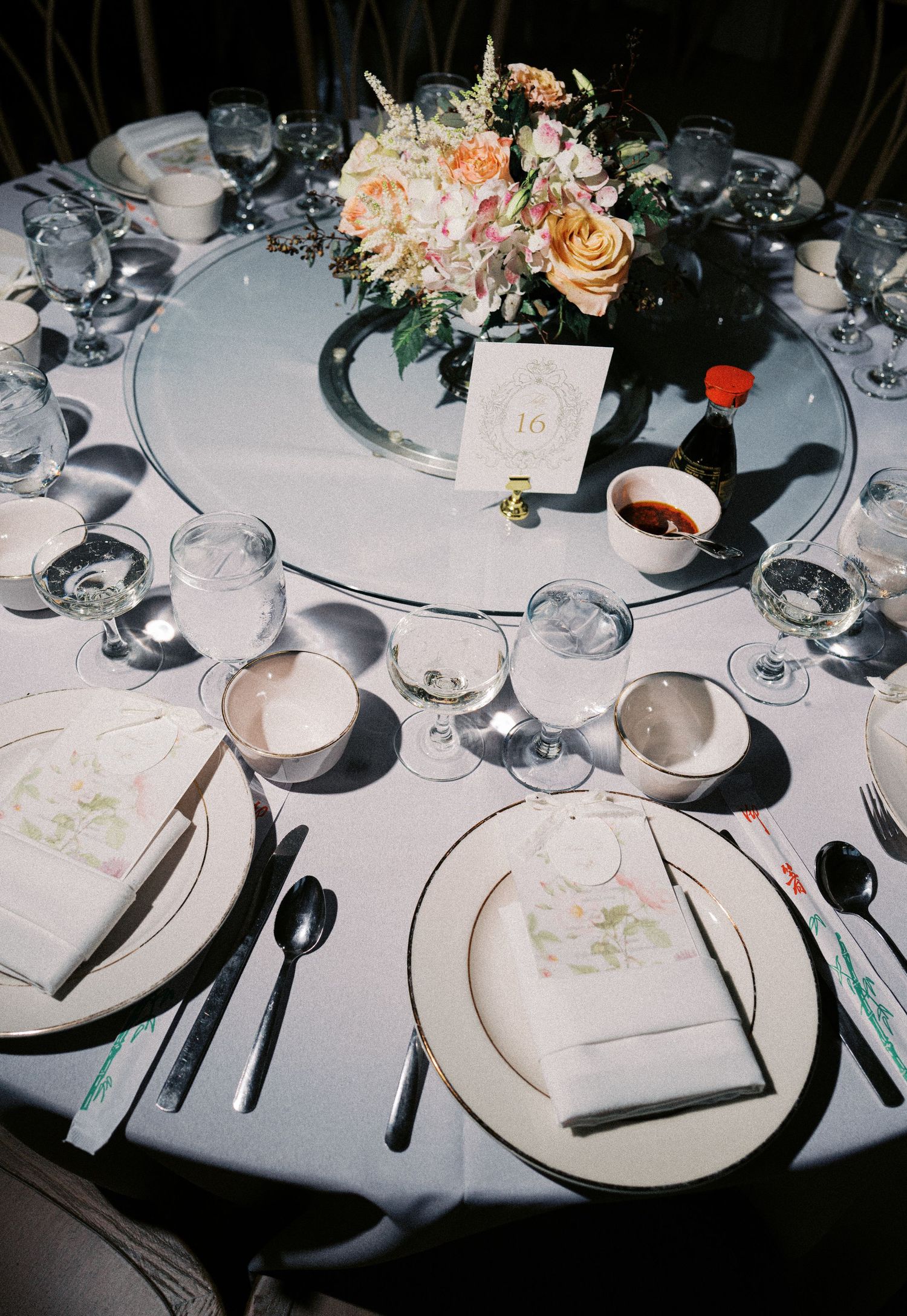 Elegant wedding reception table settings with white linens, fine china, wine glasses, and peach floral centerpieces.