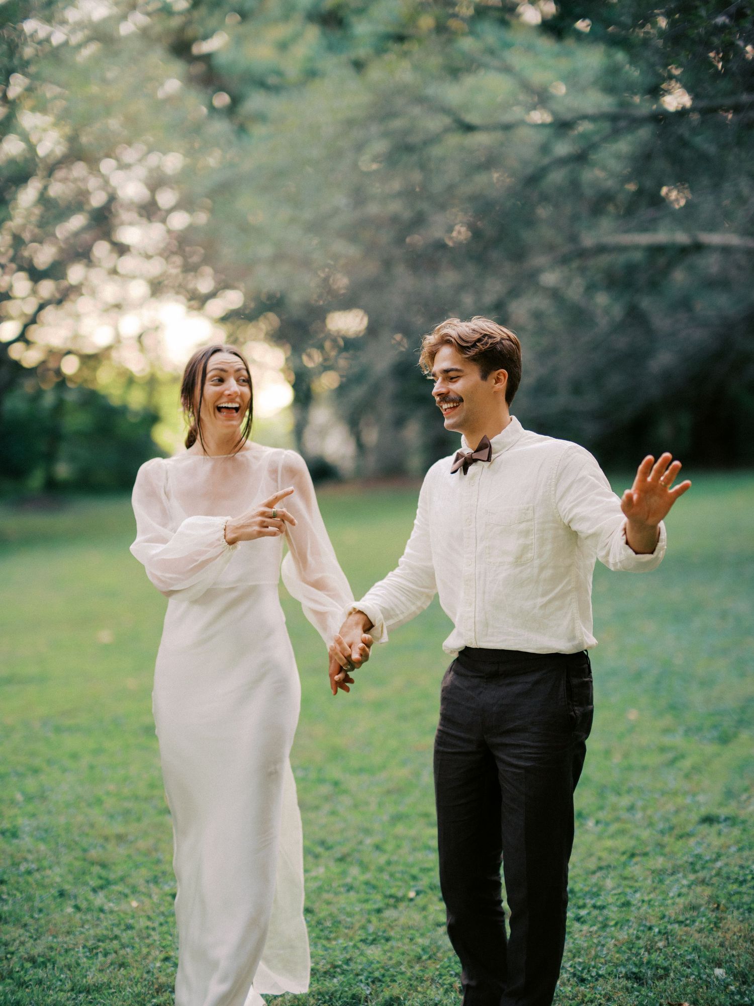Couple dances joyfully on green lawn during outdoor photo session.