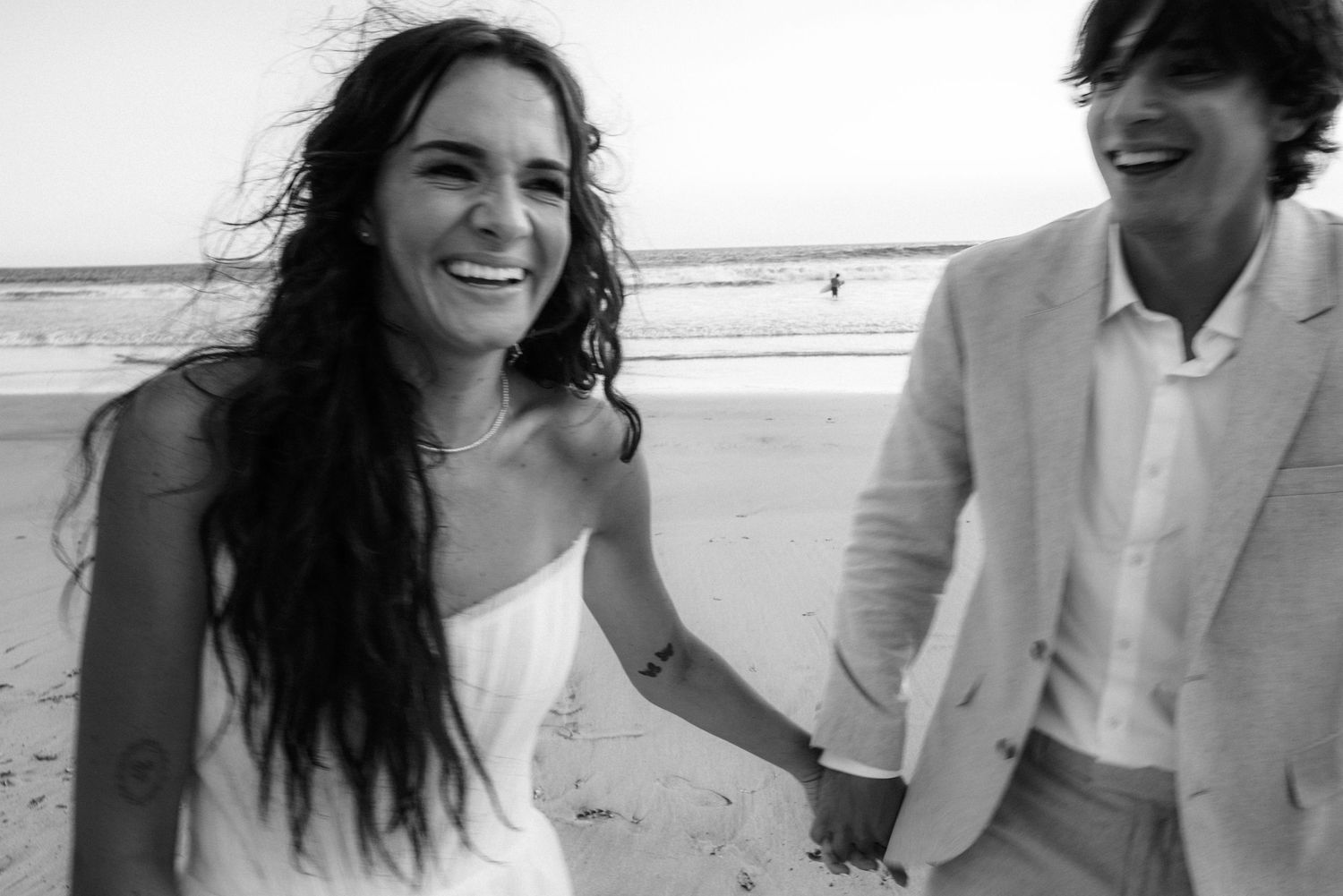 Joyful couple sharing laughter together on a sunny beach.