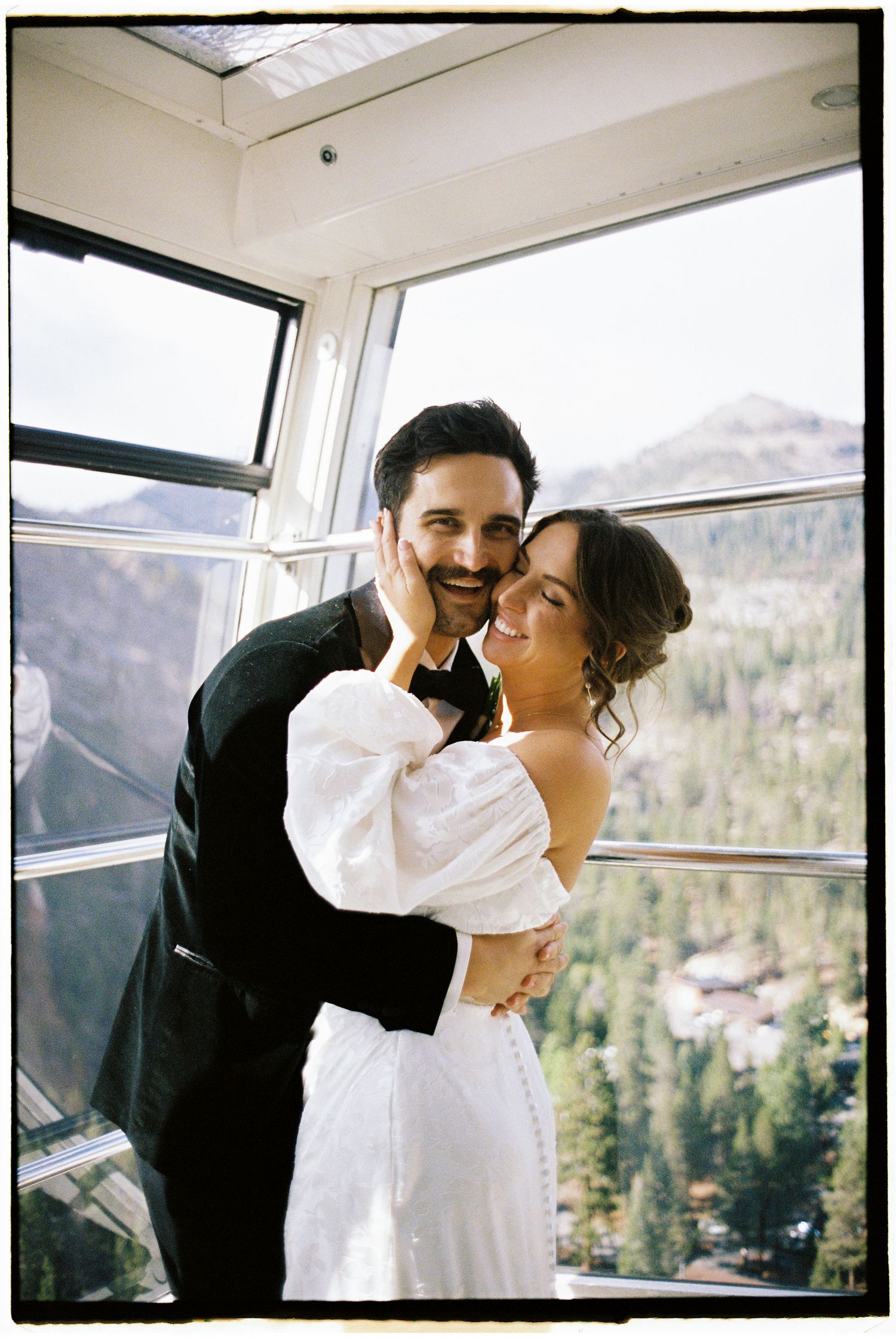A couple shares an intimate moment by large windows with mountain views.