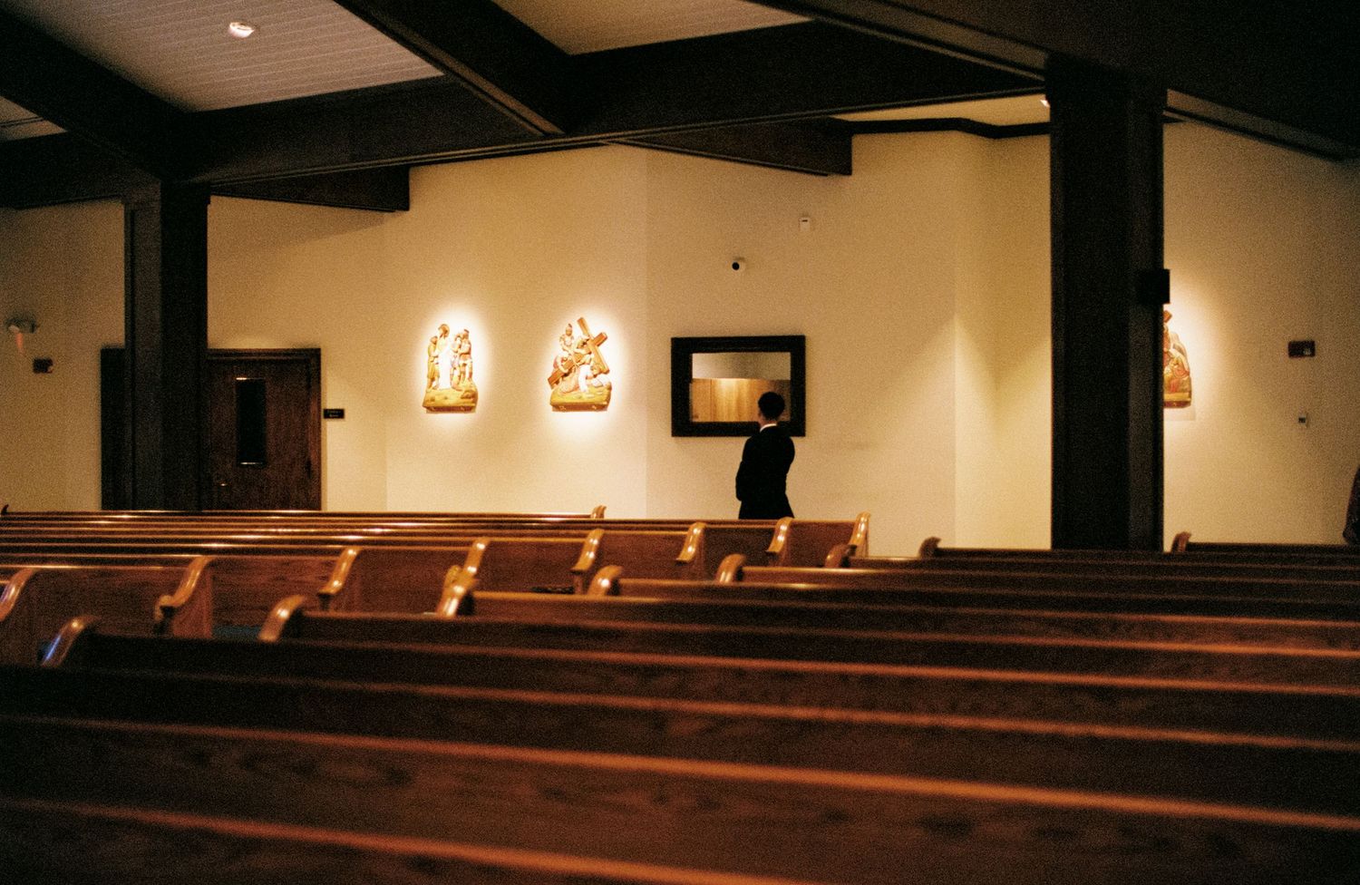 Interior view of a modern church sanctuary with exposed wooden beams and rows of empty wooden pews.