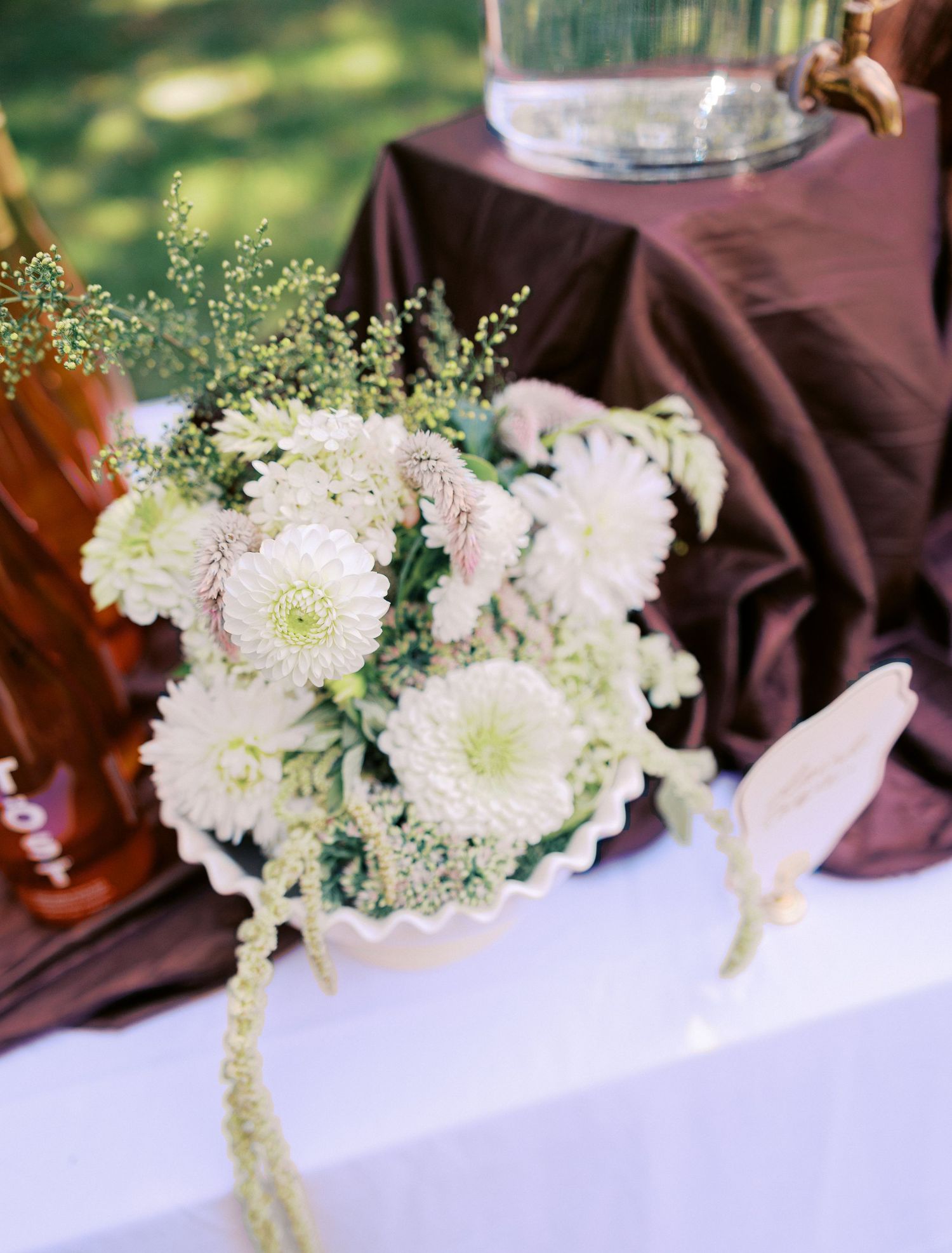 White floral centerpieces with delicate blooms arranged on tables with burgundy linens.