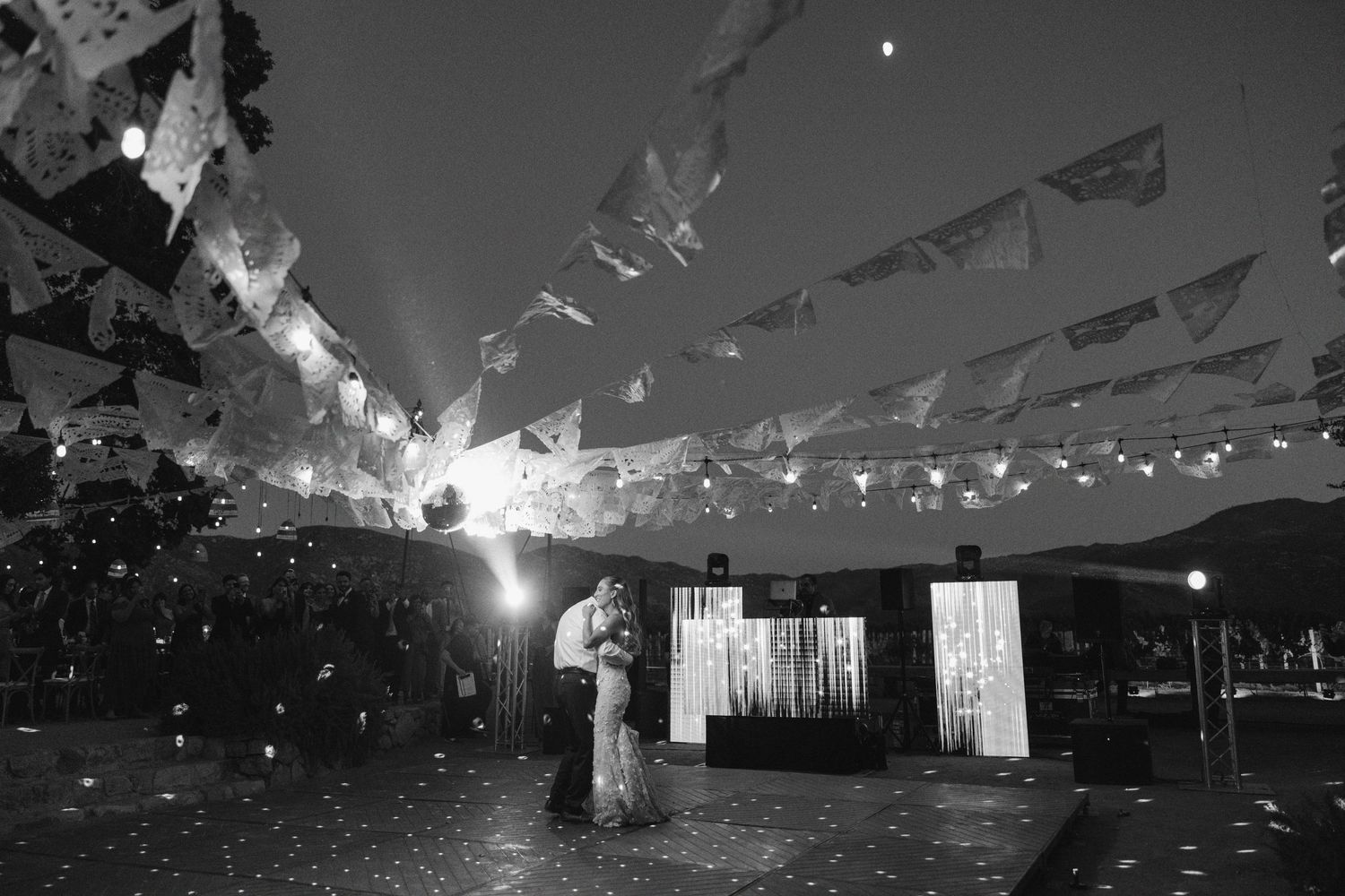 Black and white wedding reception venue decorated with string lights and banners creating a romantic atmosphere.