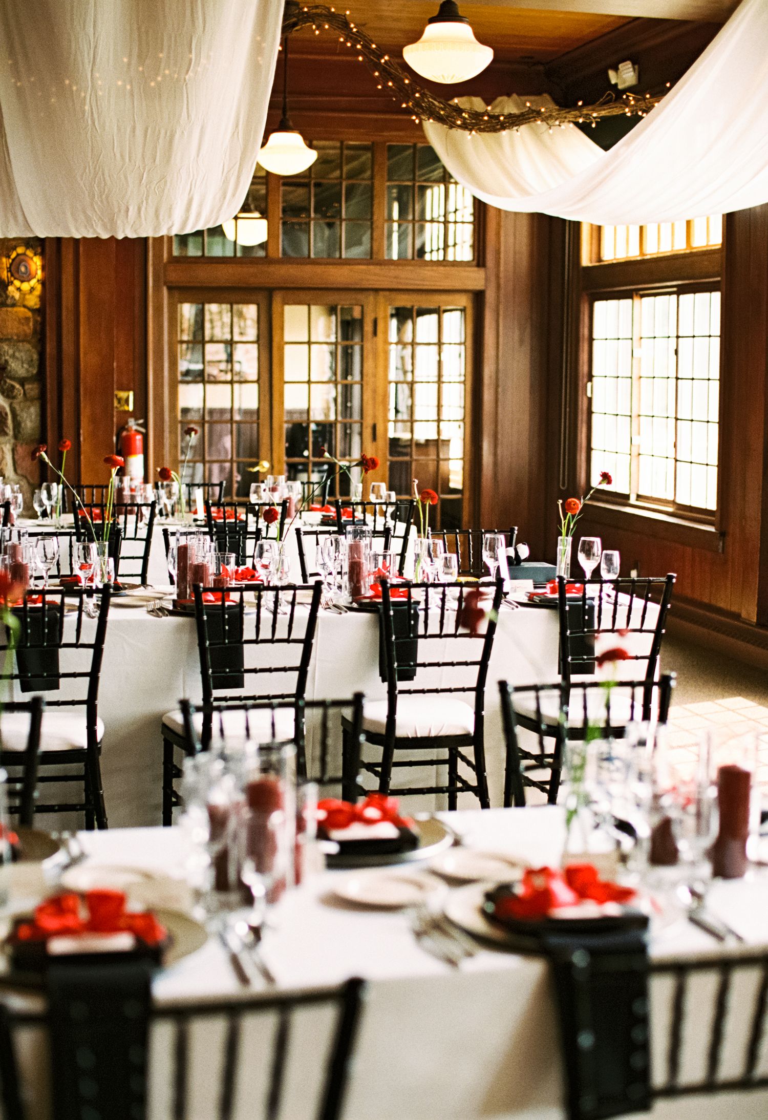 Elegant wedding reception venue with dark wood walls and white draped ceiling decorations.