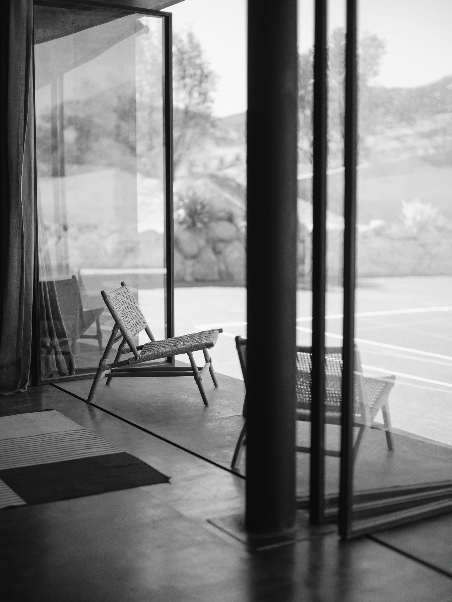 Black and white architectural interior showing modern glass windows and lounge chairs in a minimalist space.