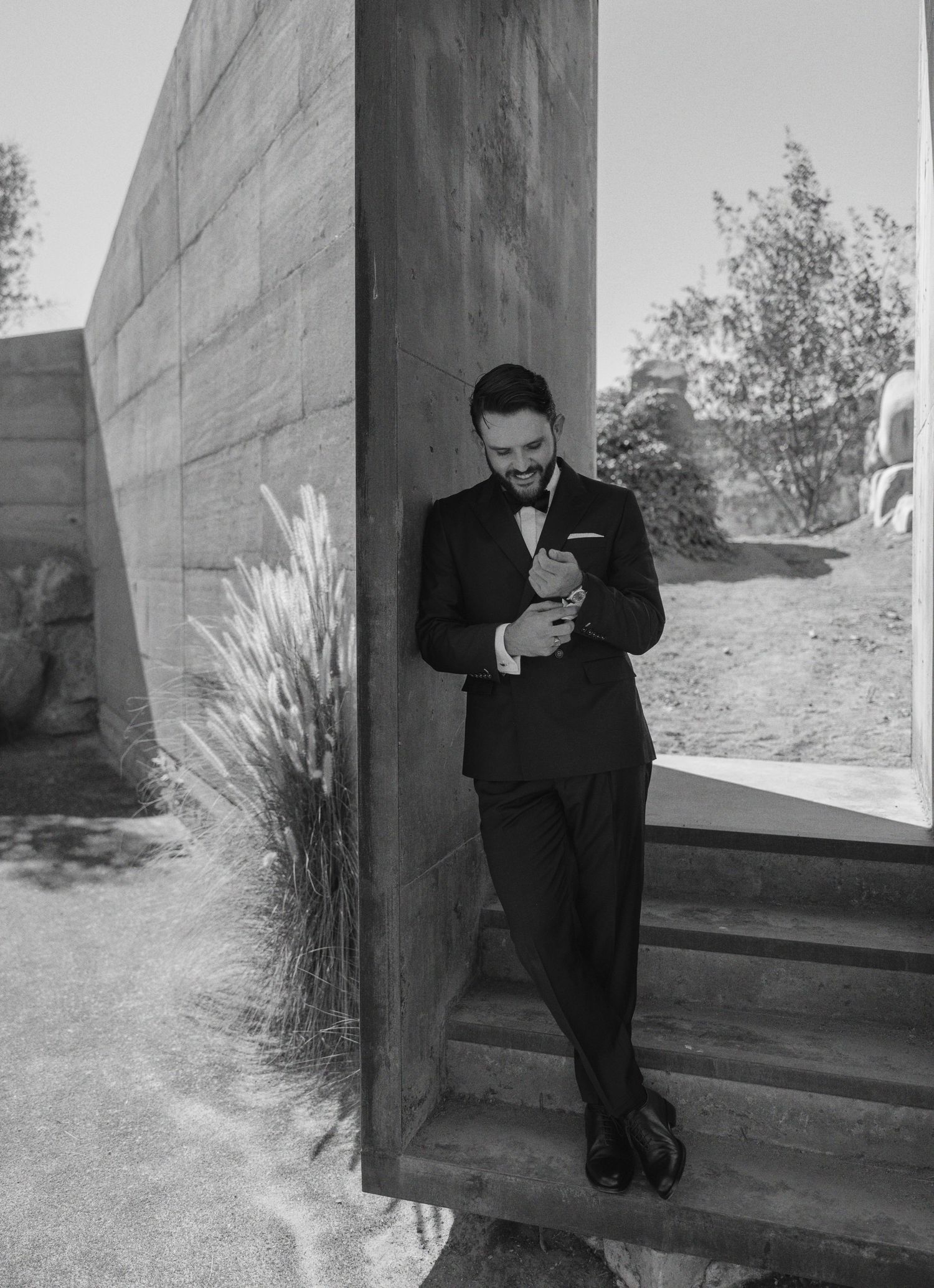 A series of black and white photos showing someone in dark clothing leaning against a concrete wall outdoors.