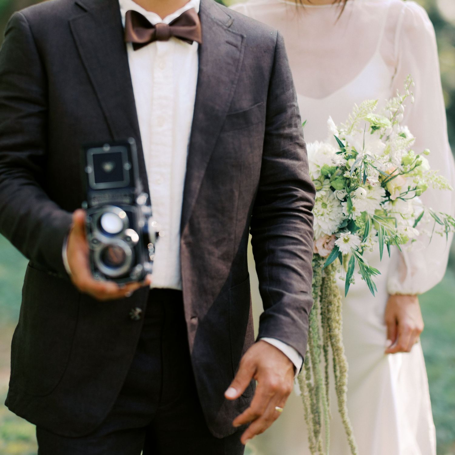Close-up details of formal wedding attire with a dark suit and white floral bouquet.