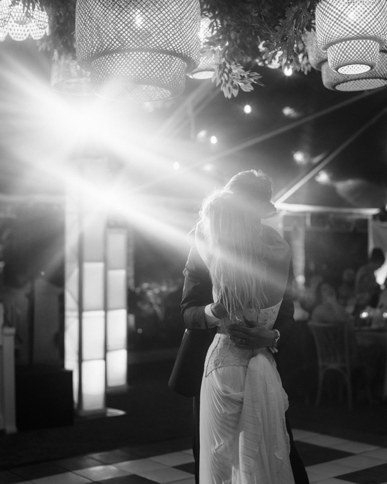 A black and white wedding photo sequence showing a couple dancing together in romantic lighting at their reception.