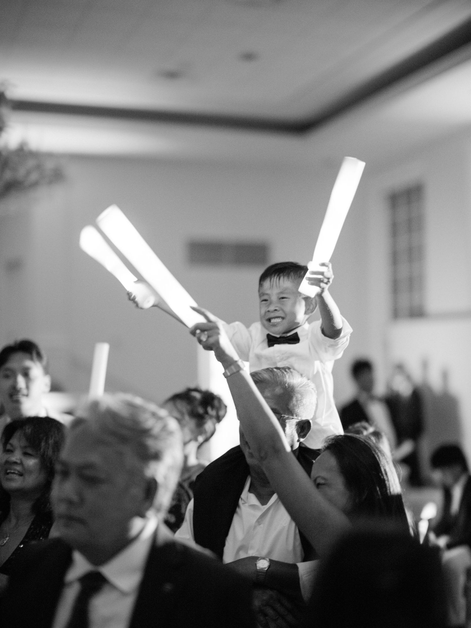 Crowd at an indoor event with glowing light sticks being waved enthusiastically in celebration.