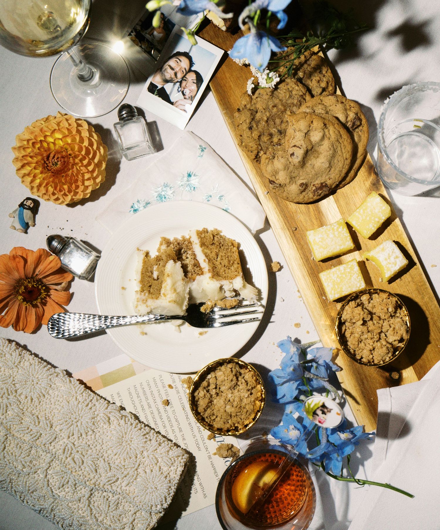 Overhead view of cookies, flowers, and decorative items arranged on a light surface with natural lighting.