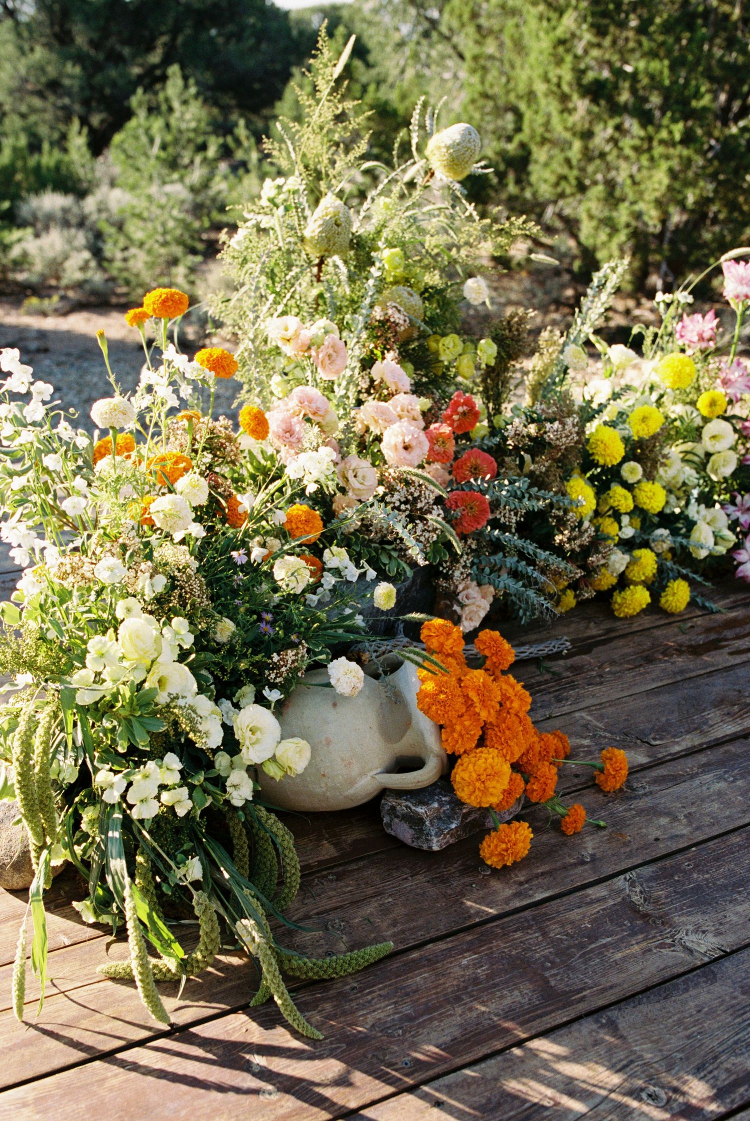 Colorful floral arrangements with marigolds and white flowers displayed on rustic wooden planks.
