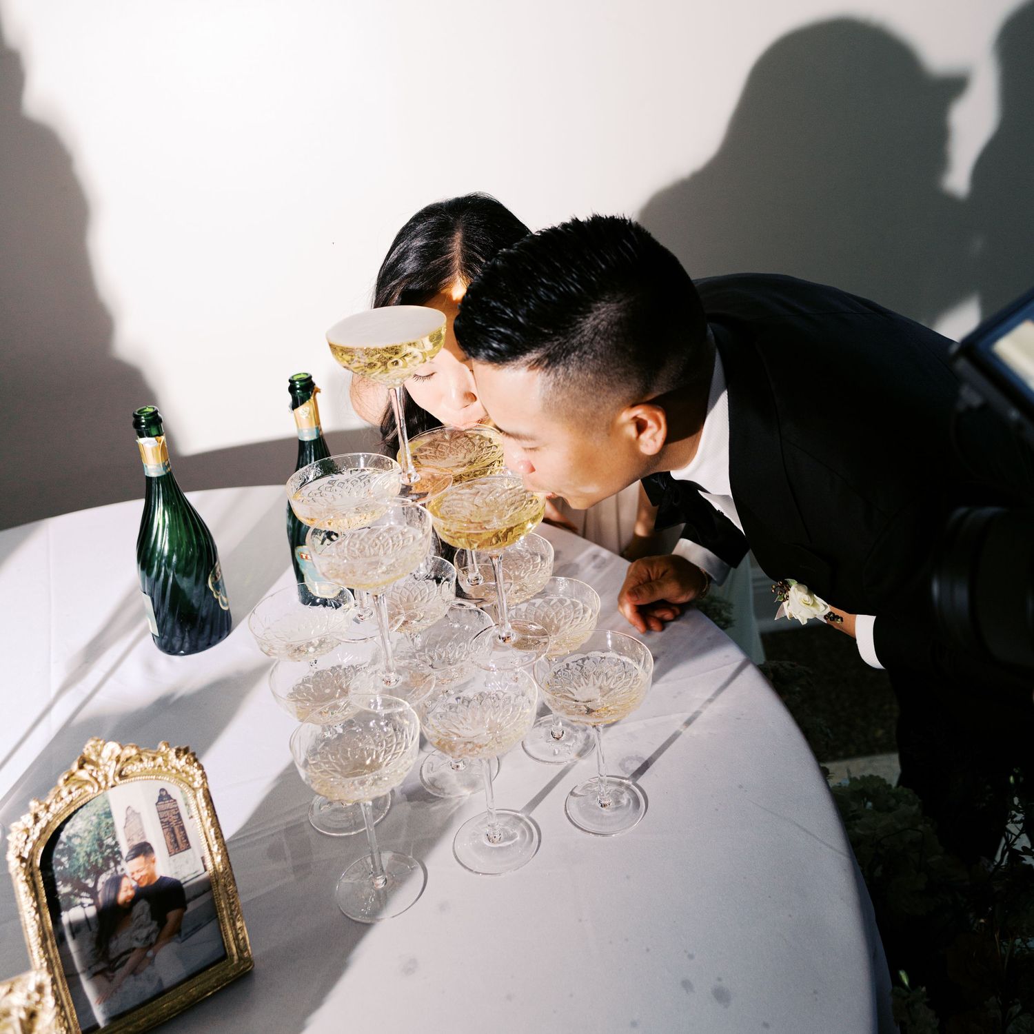 Elegant champagne tower setup with crystal coupes being arranged on a white table.
