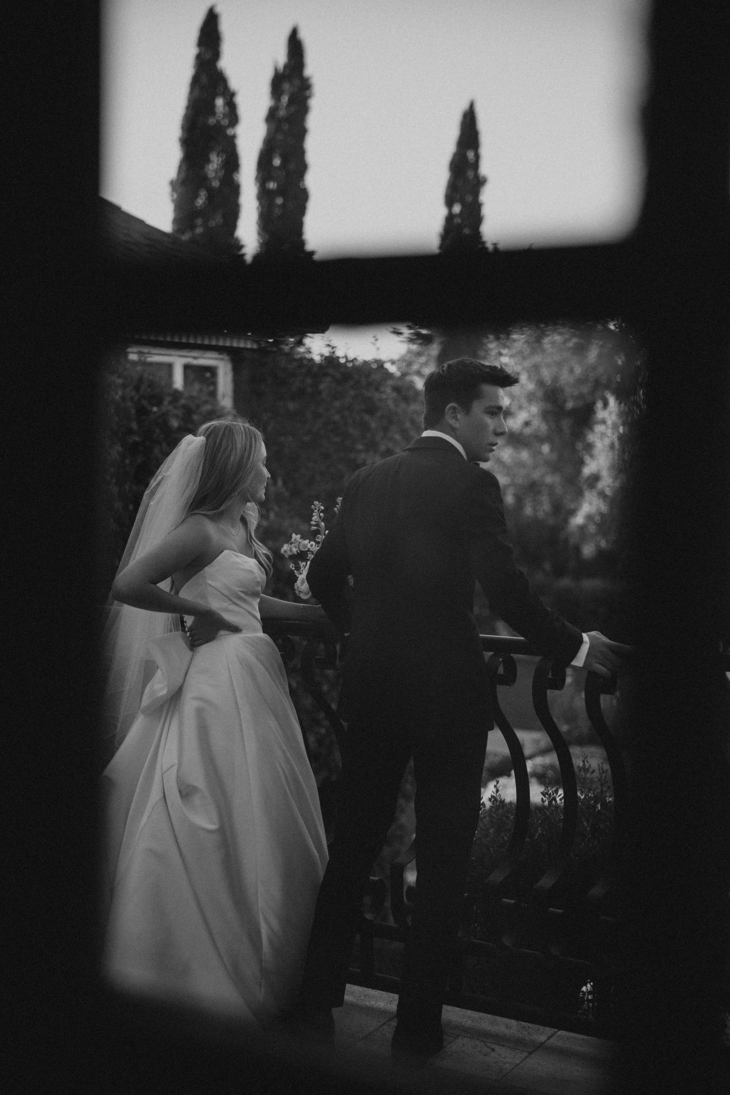 A romantic black and white wedding scene with a couple sharing a drink together in an outdoor garden setting.