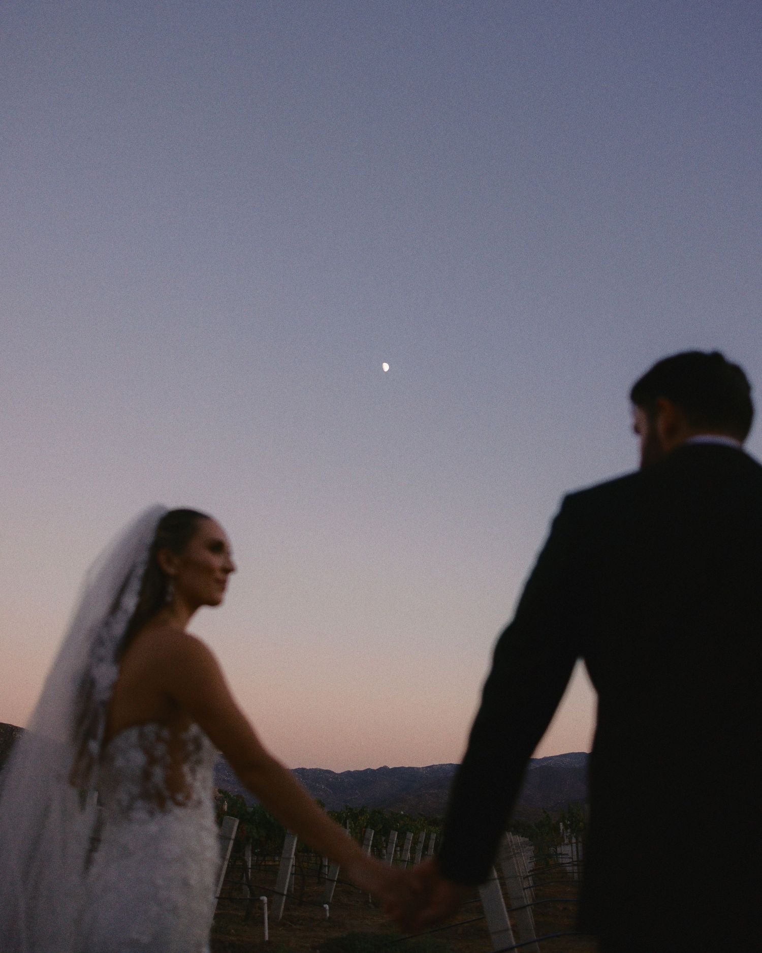 A couple shares a romantic moment at sunset with a veil flowing in the breeze.