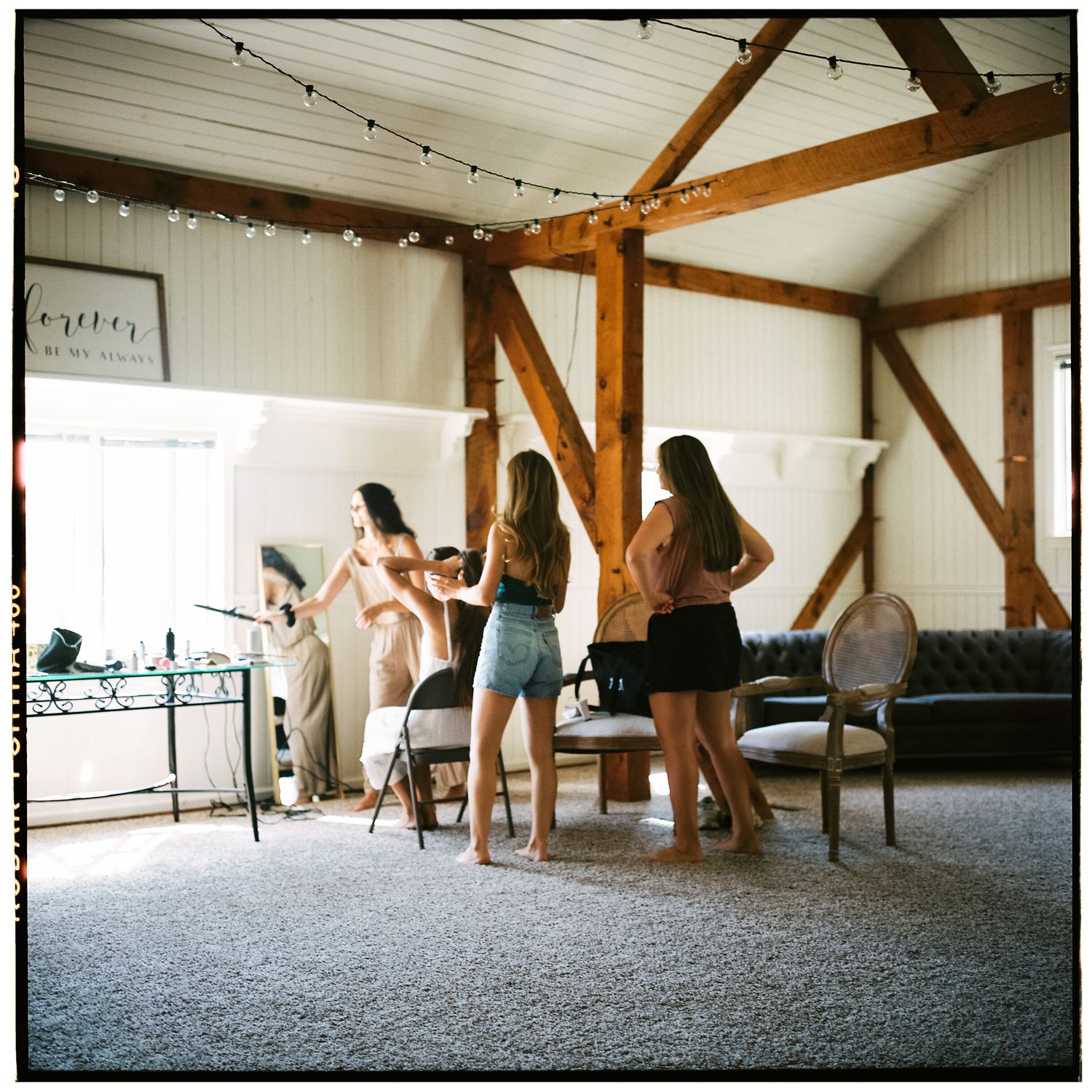 Dance party in a rustic barn venue with exposed wooden beams and string lights overhead.