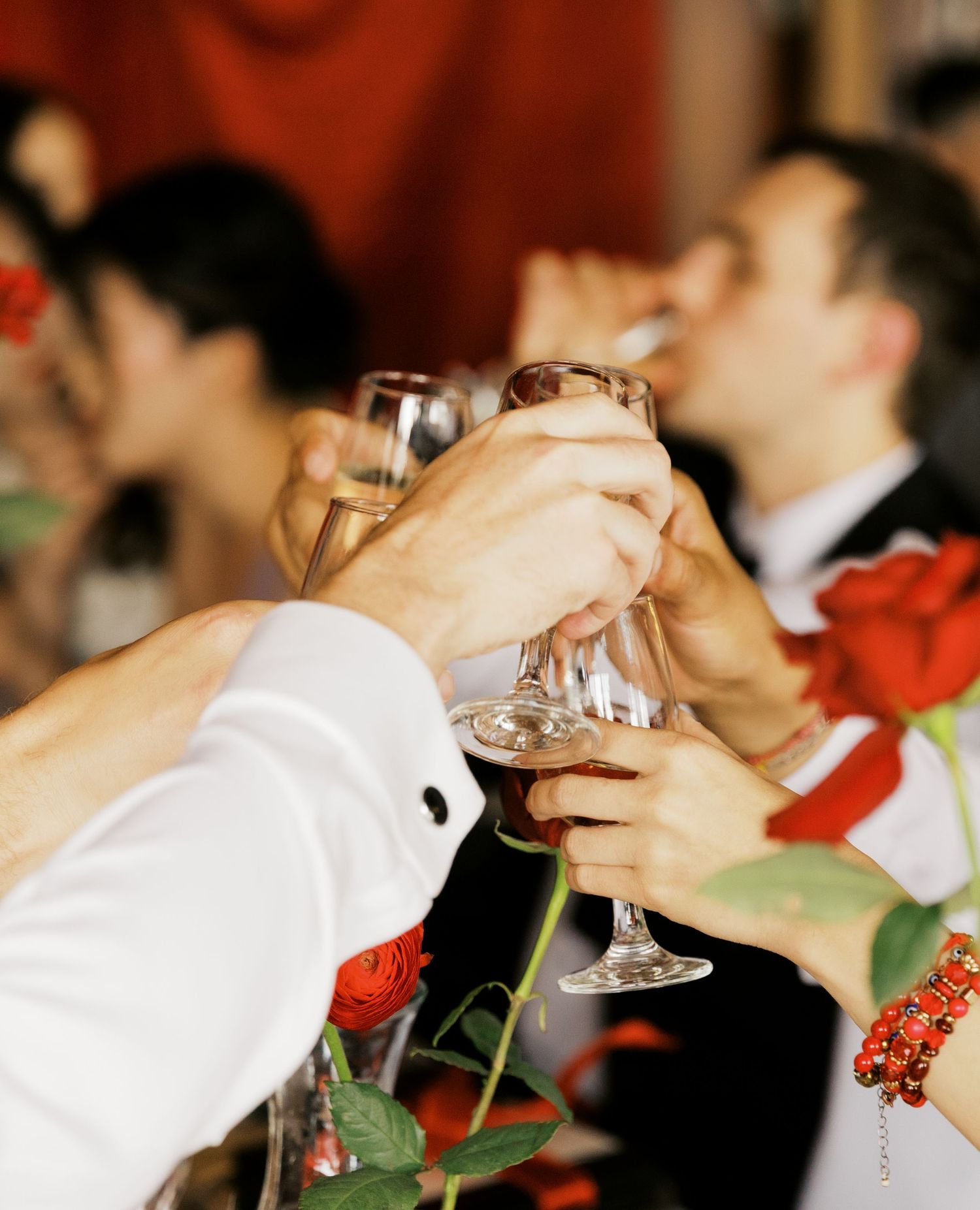 Close-up details of wine glasses and table settings with red floral accents.