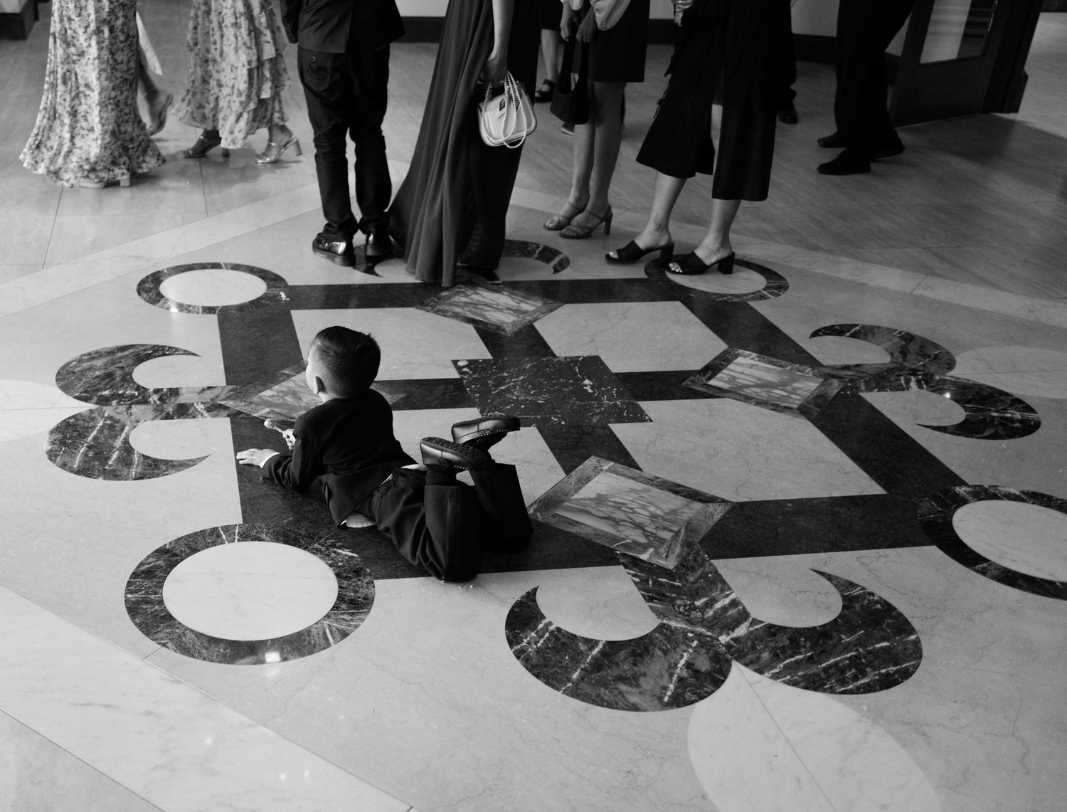 Wedding party members pose on floor in creative shadow pattern formation during reception.