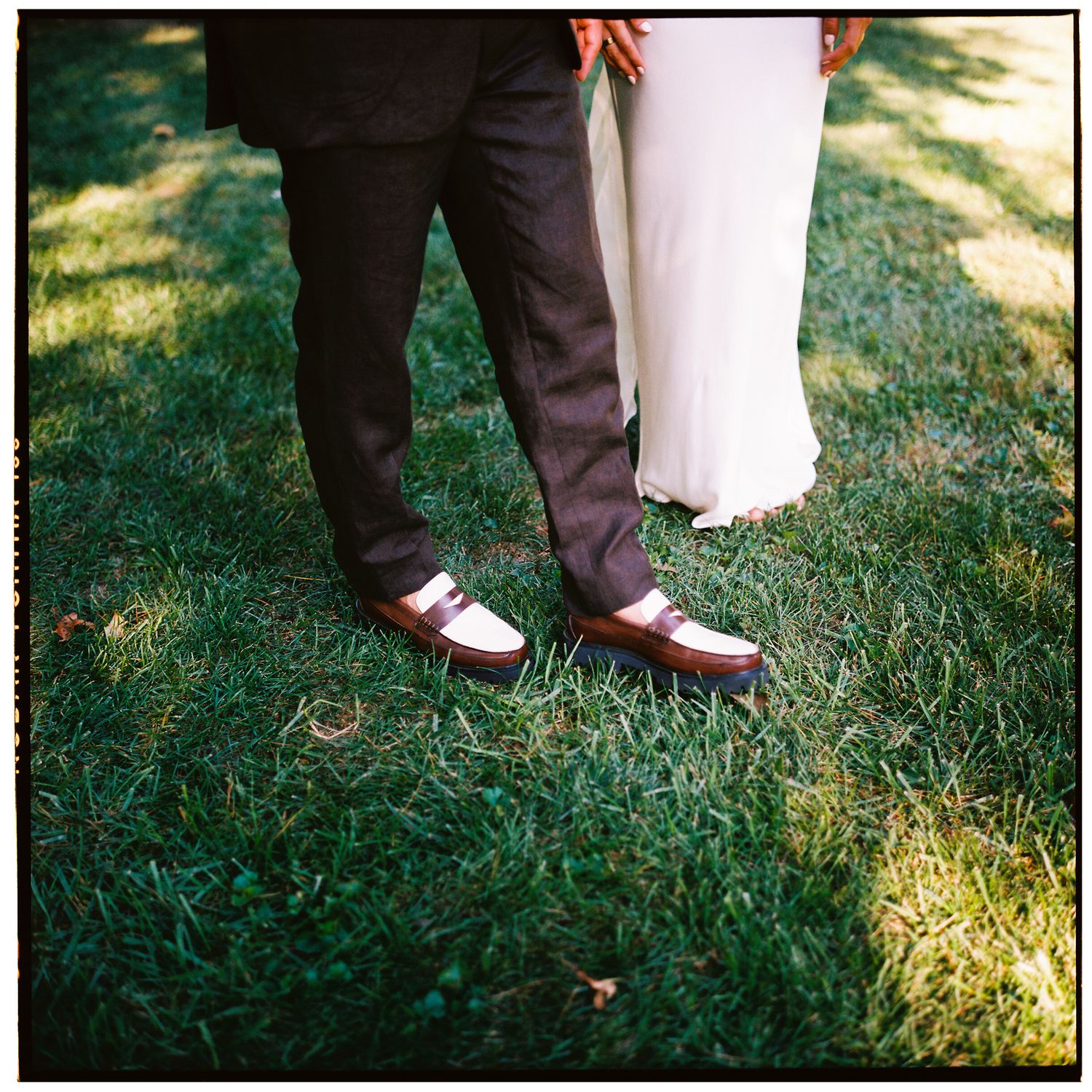 Close-up view of formal shoes on green grass at an outdoor event.