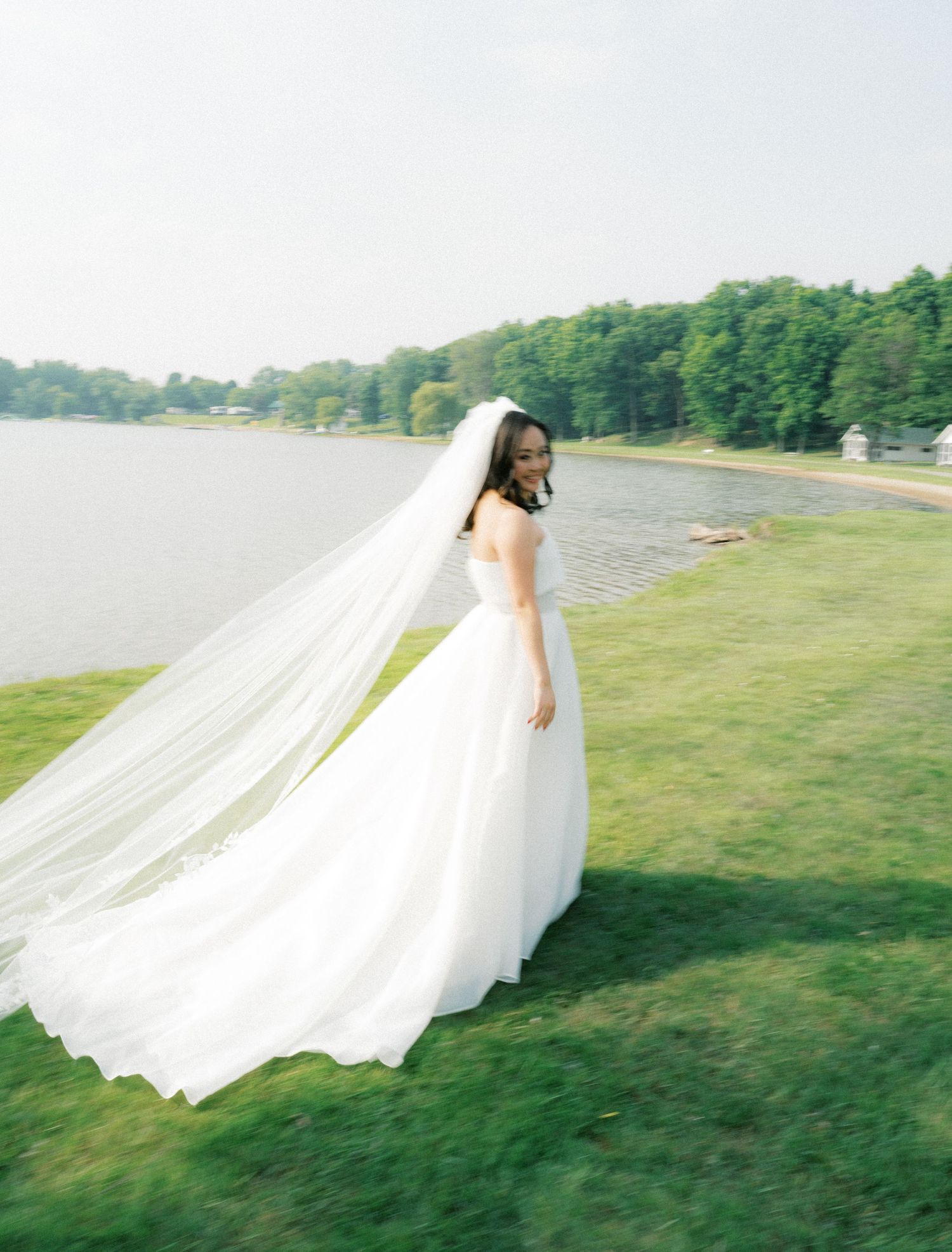 Flowing white wedding dress train billowing across a green lawn in a series of artistic shots.