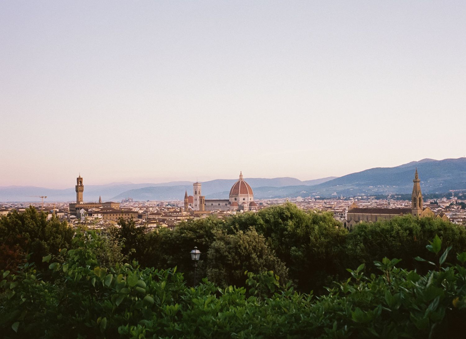 Panoramic view of Florence, Italy skyline at sunset with the iconic Duomo cathedral and historic buildings.