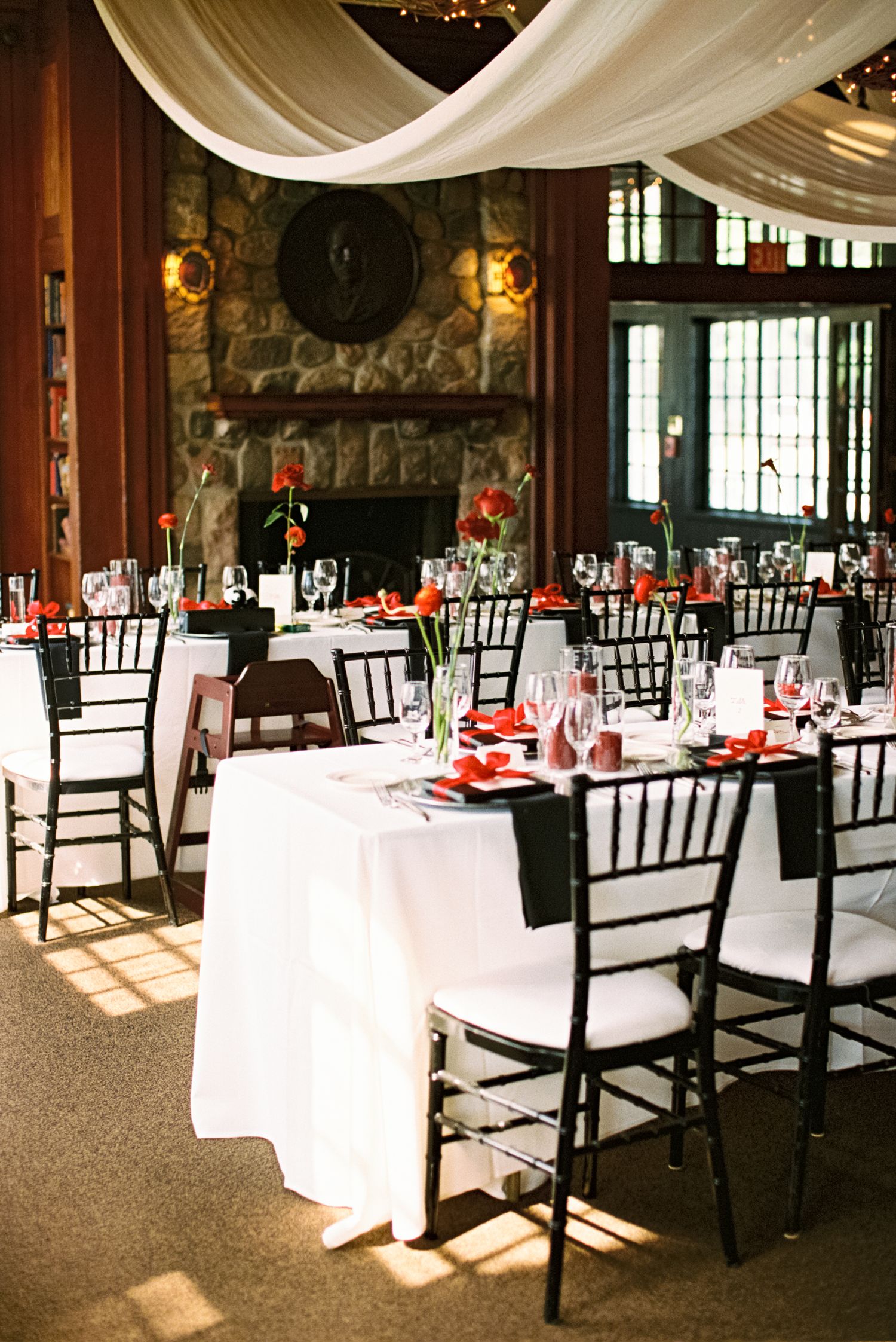 Elegant wedding reception venue with black chairs and white tablecloths.
