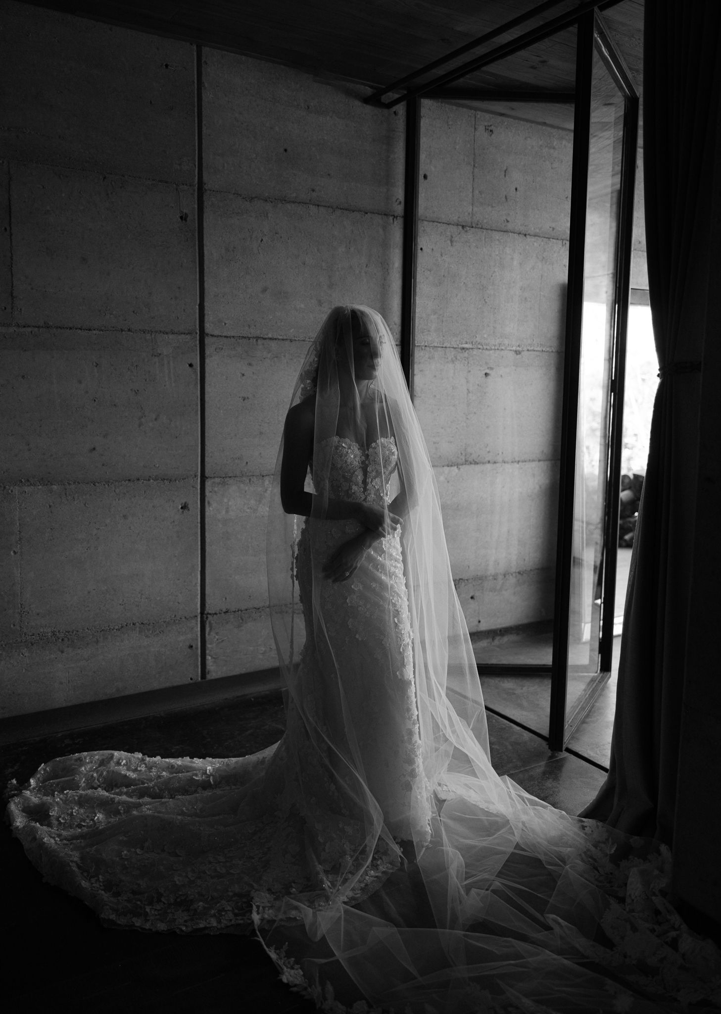 A ghostly figure in white fabric stands in a dark hallway creating an eerie atmosphere in this black and white photo series.