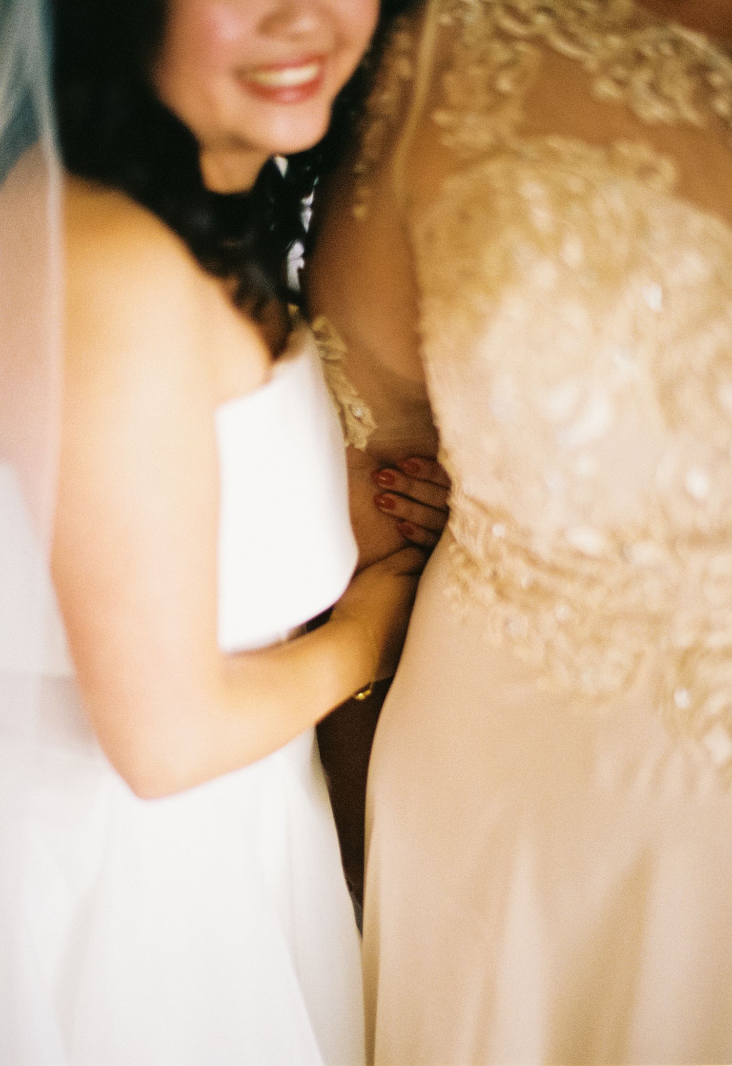 A close-up view of a white wedding dress and a champagne-colored formal gown side by side.