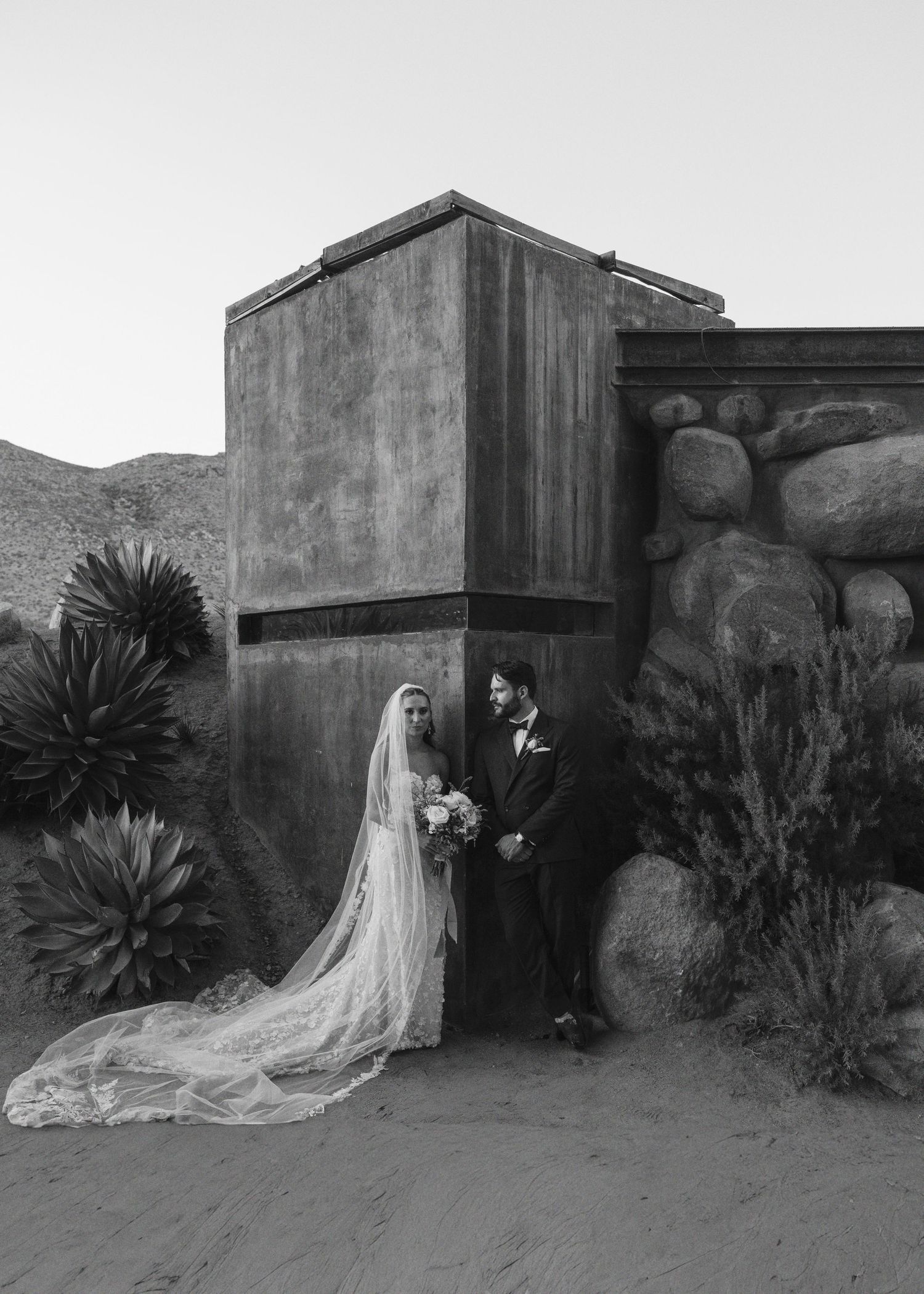 Artistic black and white sequence showing figures against concrete walls and desert landscaping.