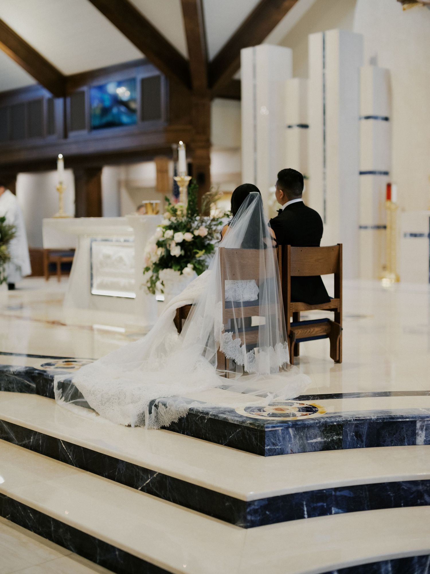 Modern wedding reception table setup with white decor and hanging pendant lights in an elegant venue.