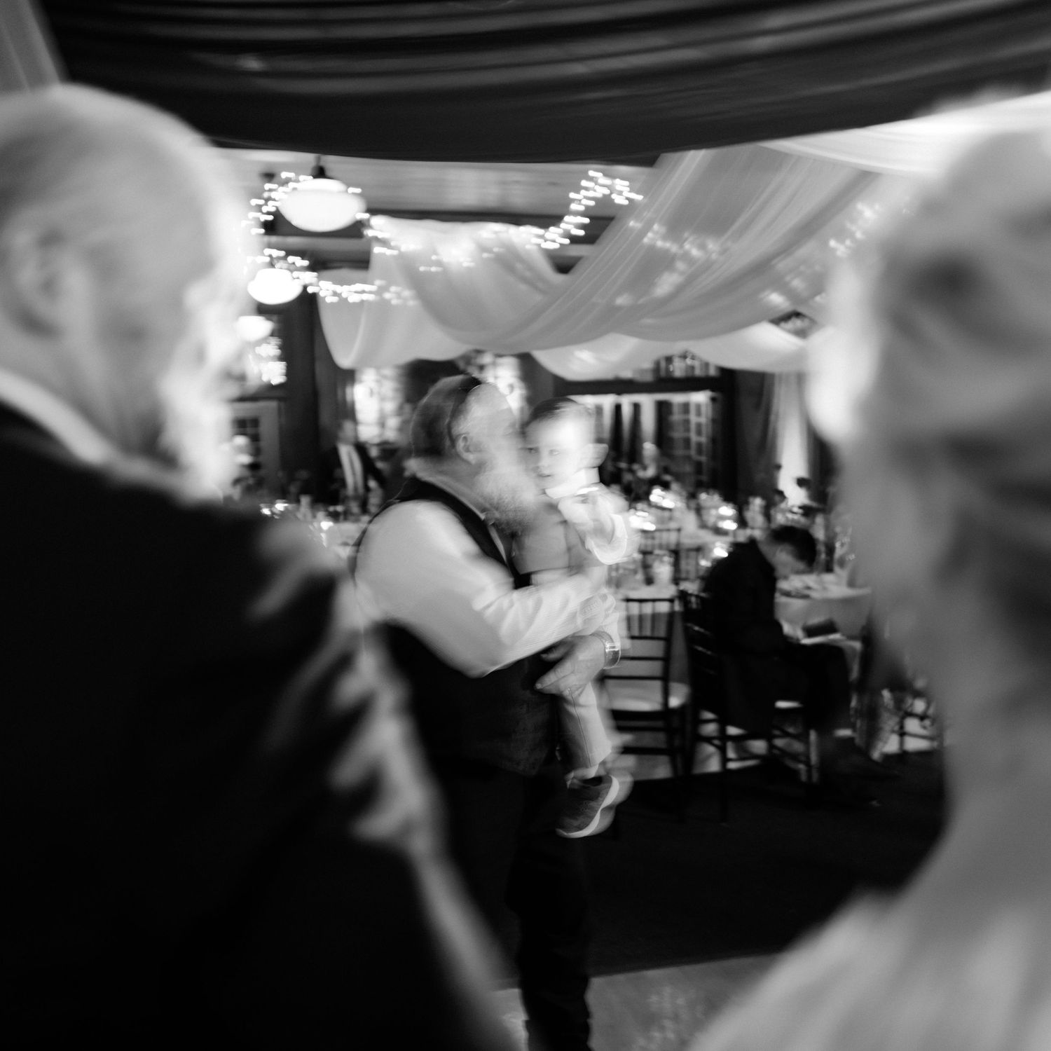 Black and white photo of guests dancing at an elegant wedding reception.