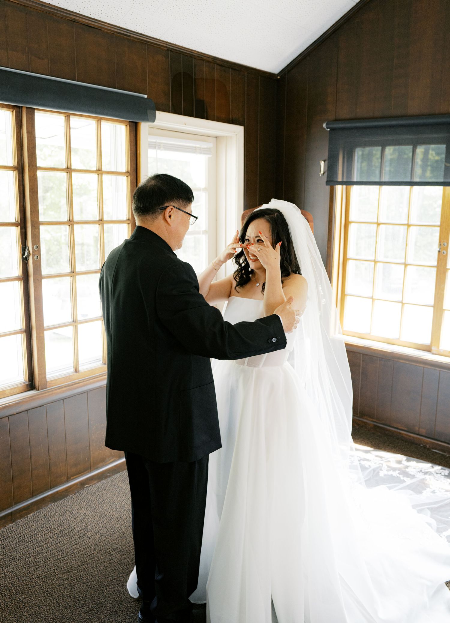 An emotional moment captured in a sunlit room with wooden paneling and windows.