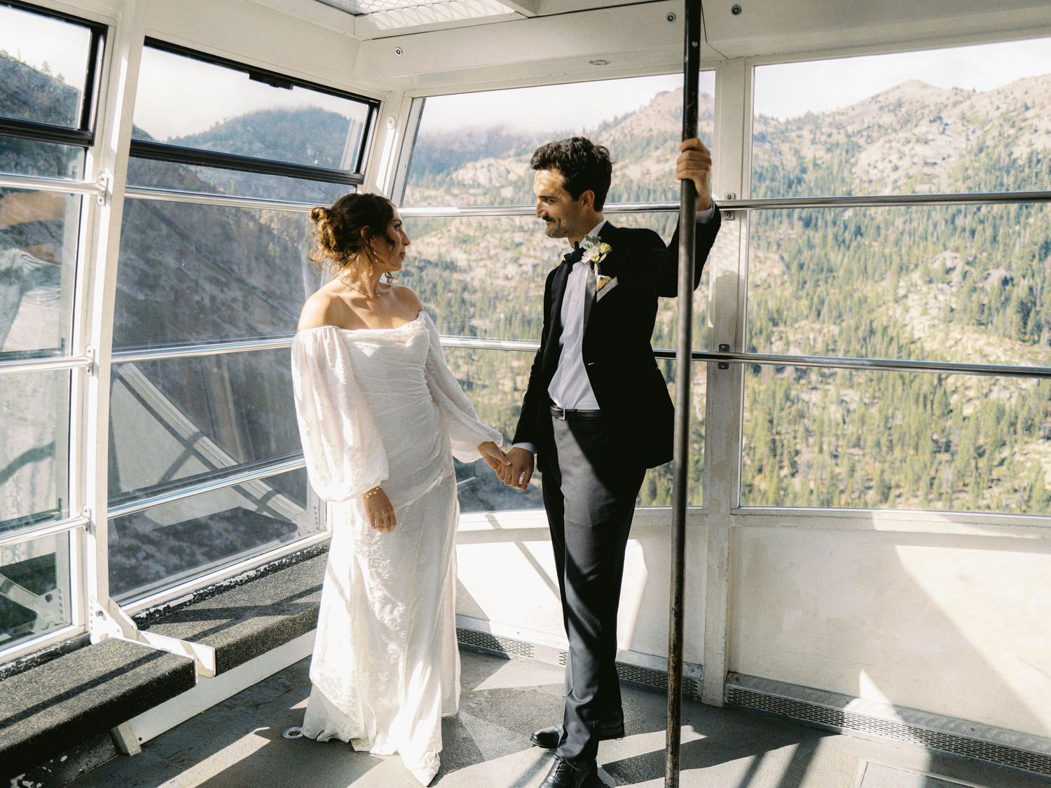 Couple shares intimate moments in a bright sunlit room with panoramic mountain views through floor-to-ceiling windows.