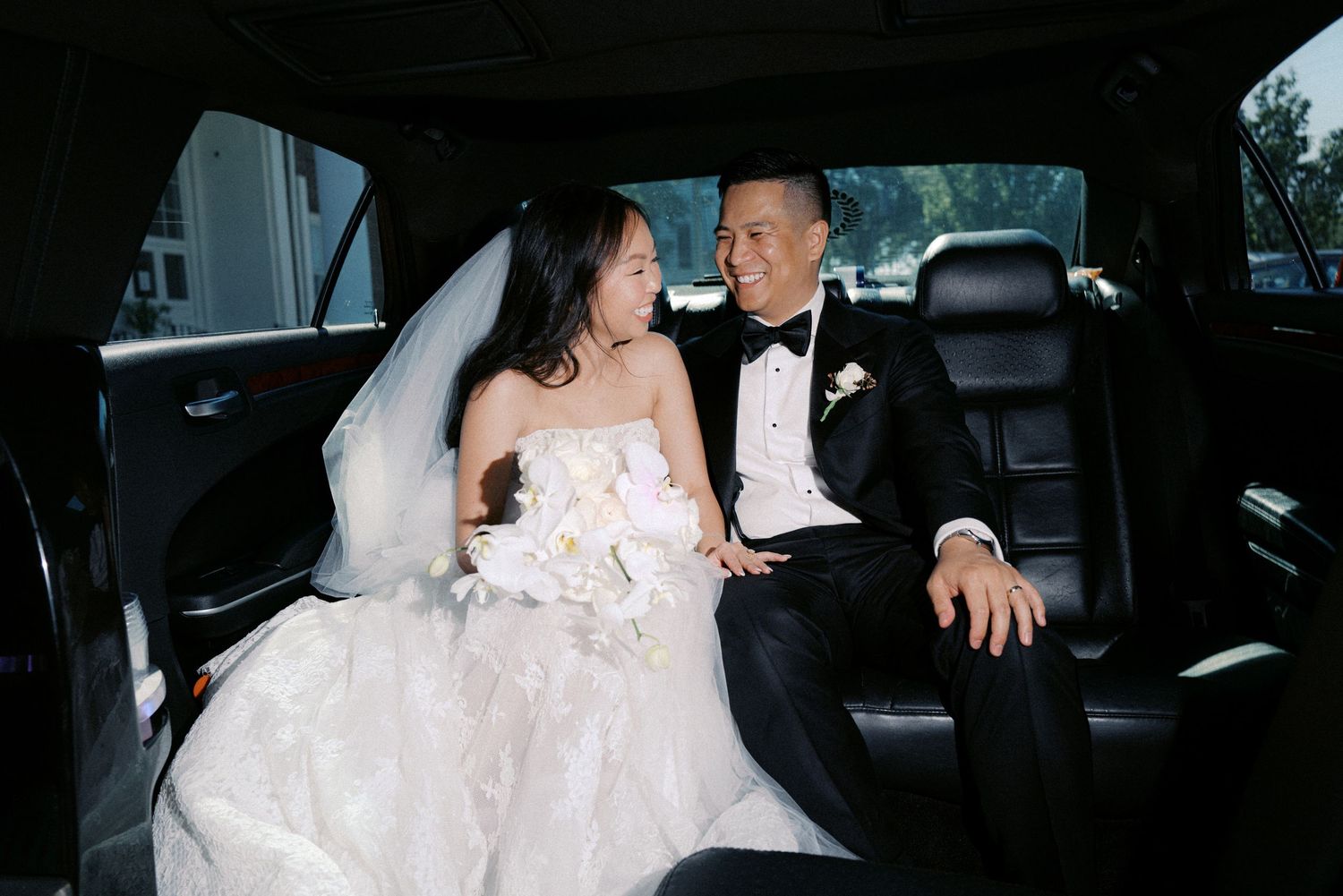 Bride and groom share intimate moments in wedding car while traveling to their celebration.