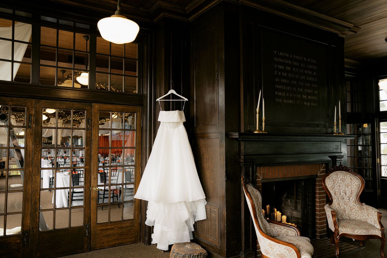 A rustic industrial wedding venue with exposed brick walls, hanging lights, and white dresses displayed on hangers.