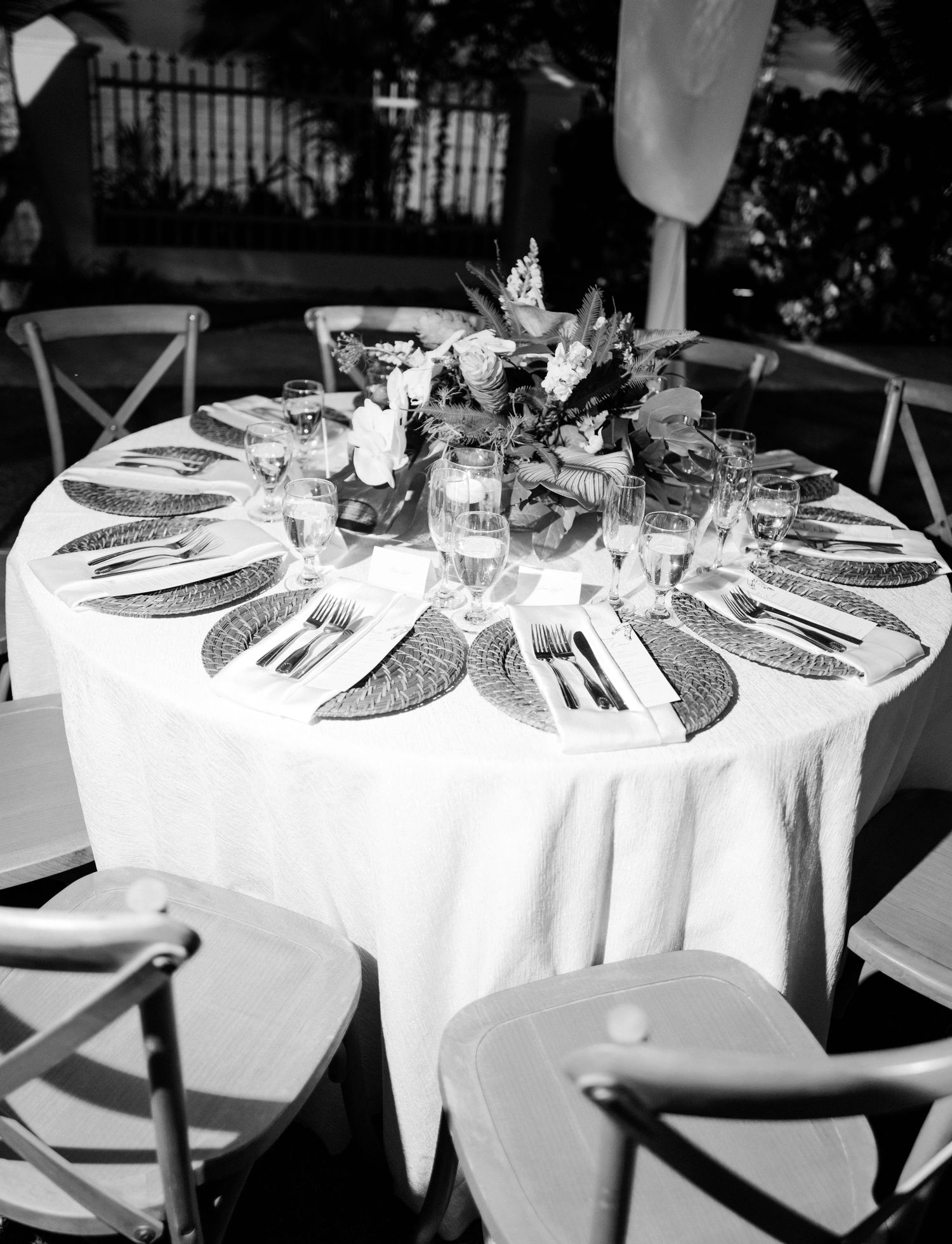 Elegant round dining table set for a wedding reception with white linens, place settings and floral centerpiece.