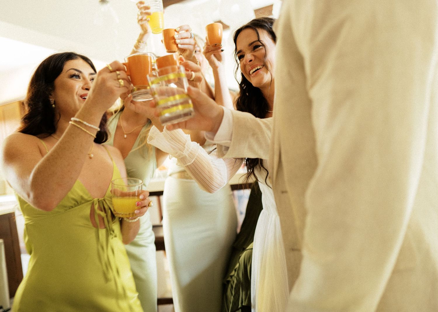 Wedding guests raise their glasses in celebration during a joyful toast at an indoor reception.