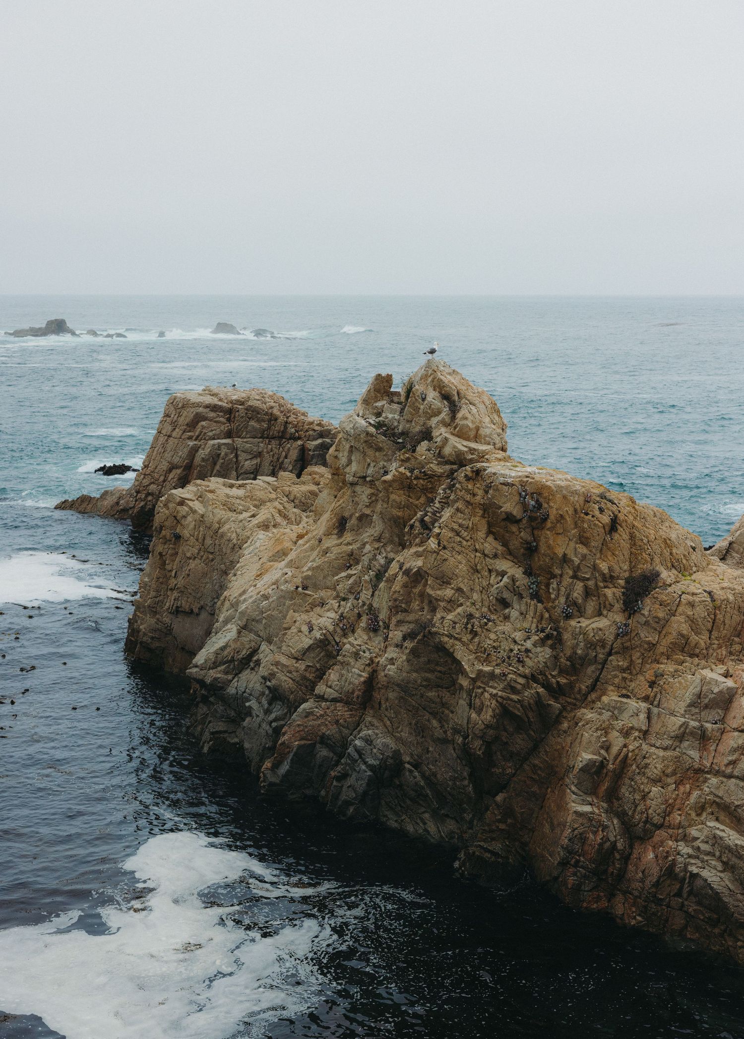 Panoramic sequence of rugged coastal cliffs and rock formations jutting into the misty blue ocean waters.