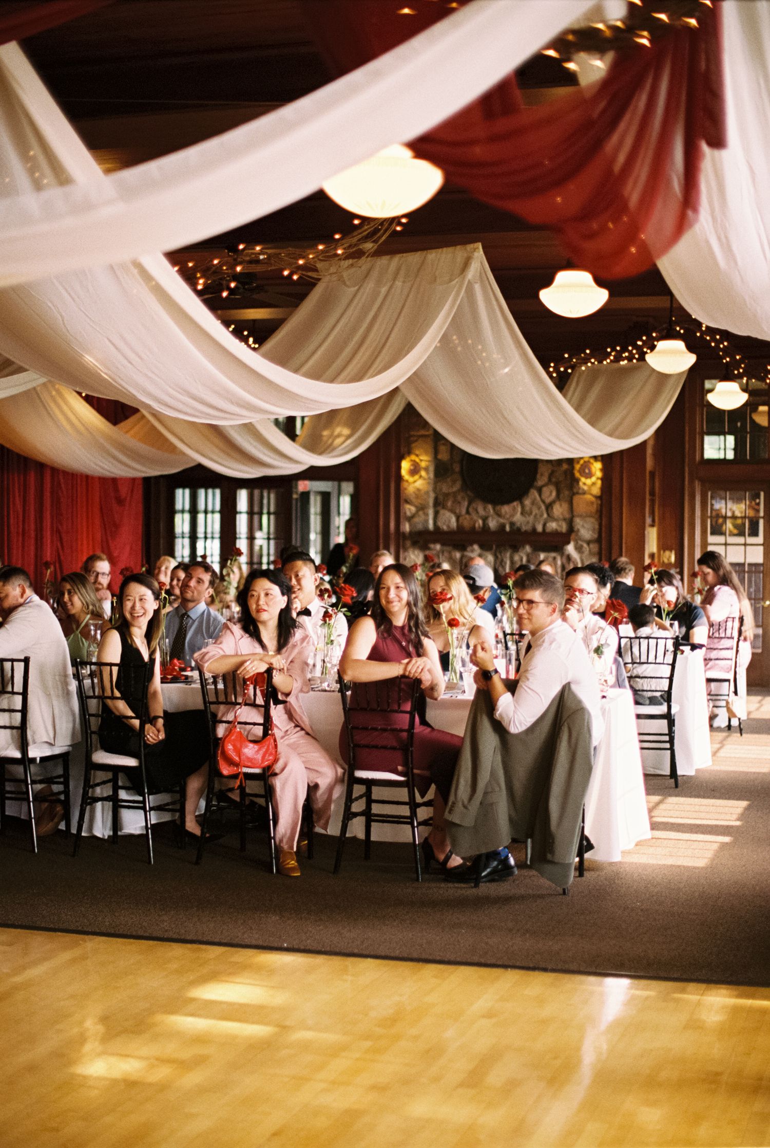 Wedding reception venue with white ceiling drapes and guests seated at tables during celebrations.