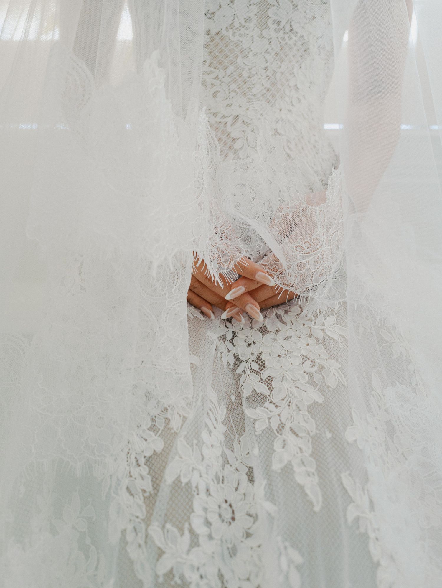 Delicate white lace and tulle wedding dress details with a peach-colored bow accent.