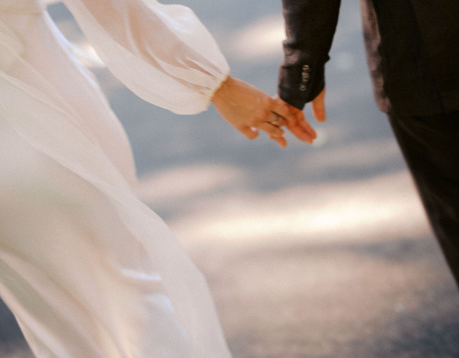 Two hands reaching towards each other against a blurred background, with one person wearing white clothing.