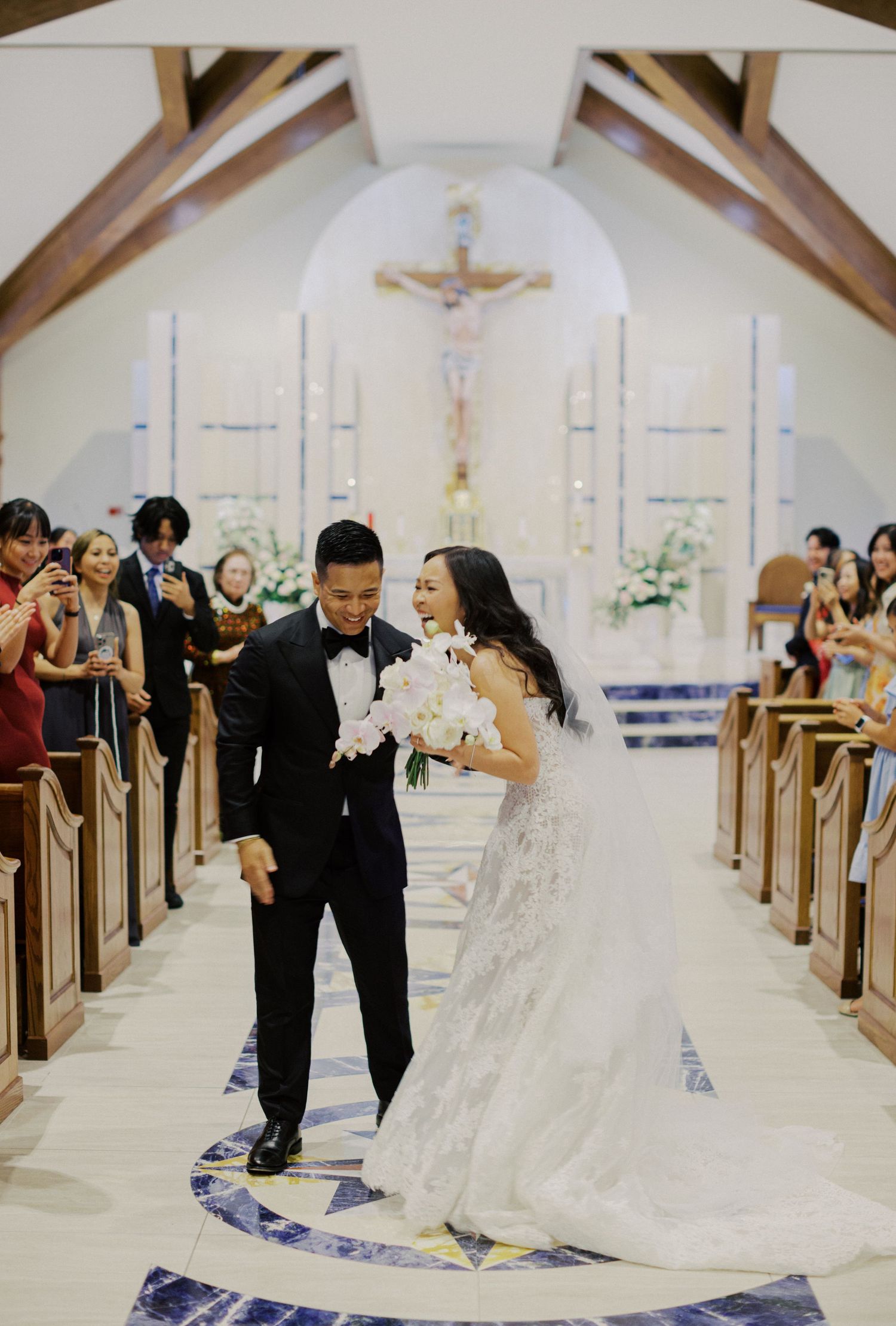 Romantic wedding couple dancing together in a beautifully decorated church with white floral arrangements.