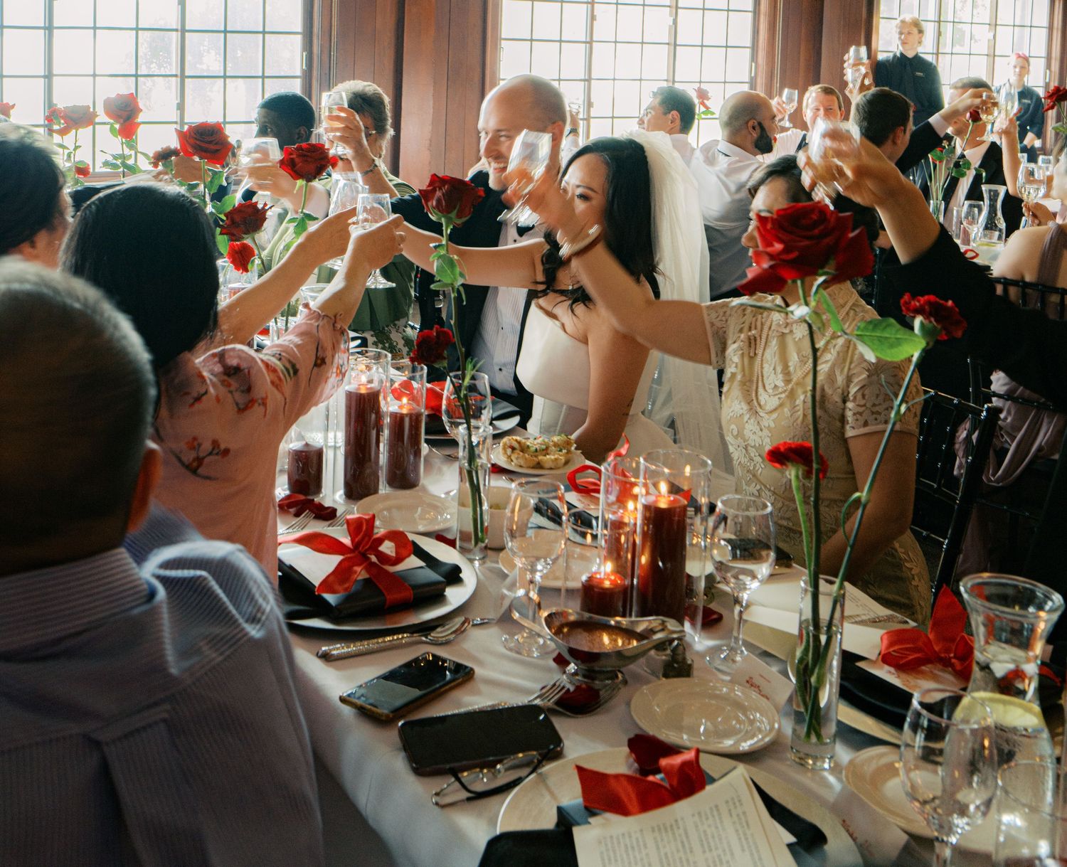 Wedding guests raise glasses in a celebratory toast during reception dinner.