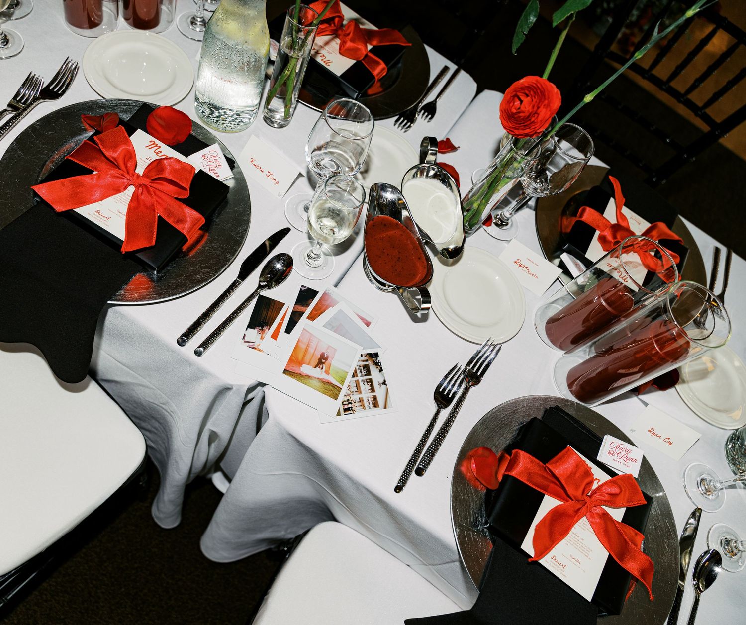 Wedding table setting with black and red decor featuring wrapped favors and glassware.