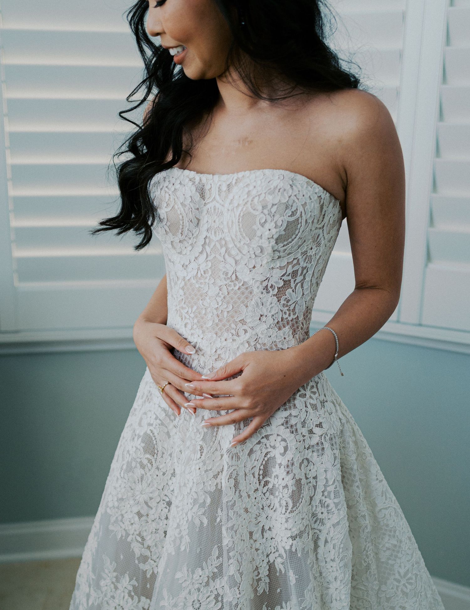 Close up of a delicate white lace wedding dress with strapless bodice and intricate floral details.