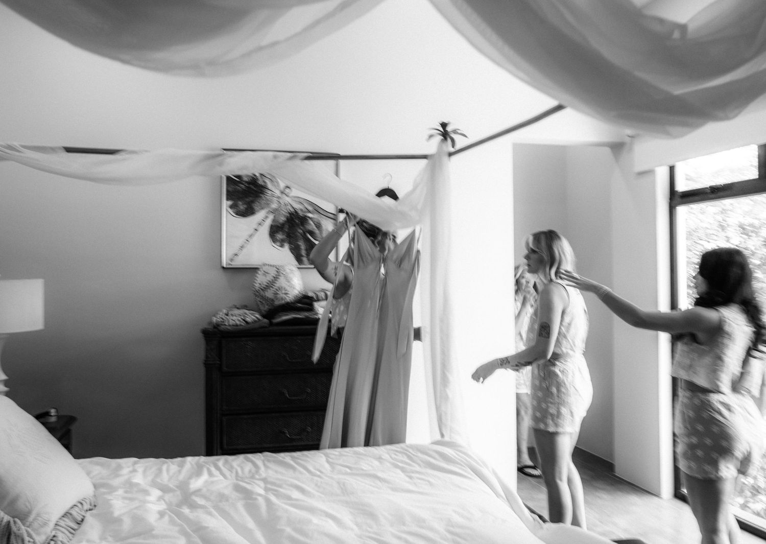 A sequence of black and white photos showing playful jumping on a bed in a bright room.