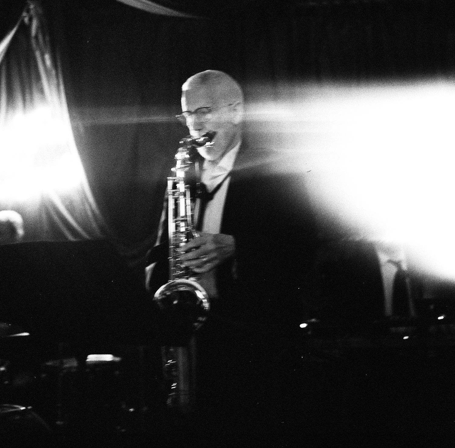 Black and white performance photography with dramatic stage lighting and silhouettes.