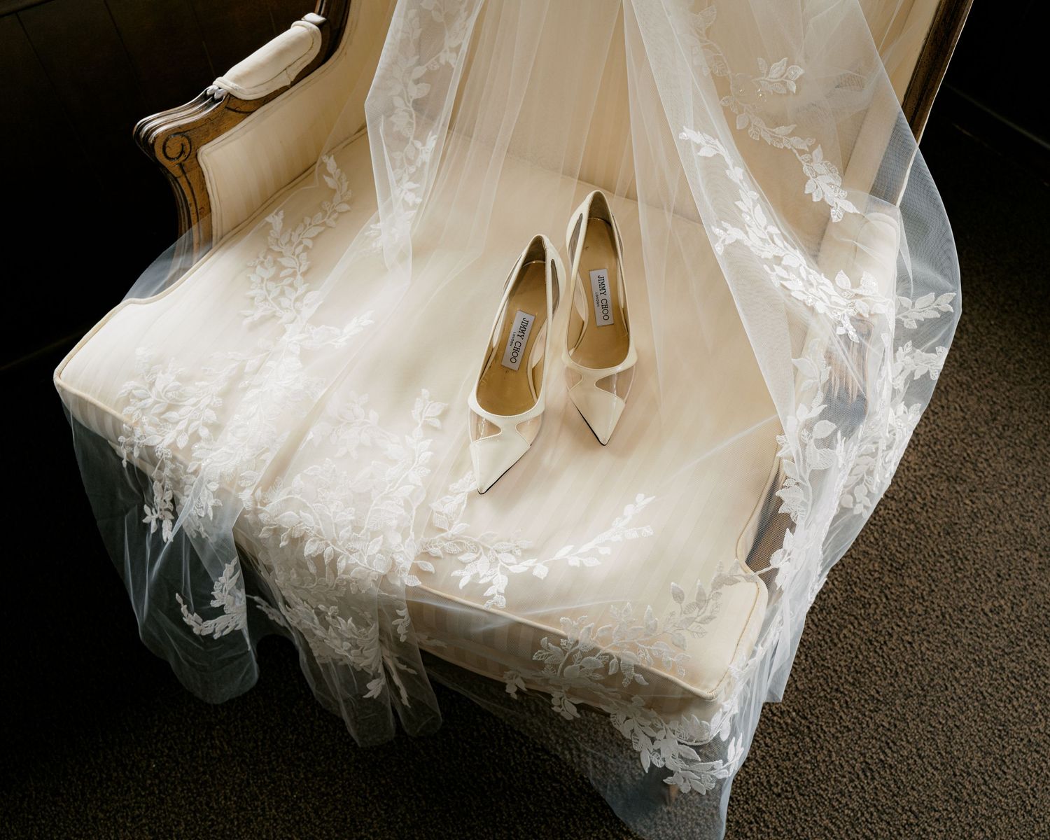 Elegant white bridal shoes rest on delicate lace veil fabric.