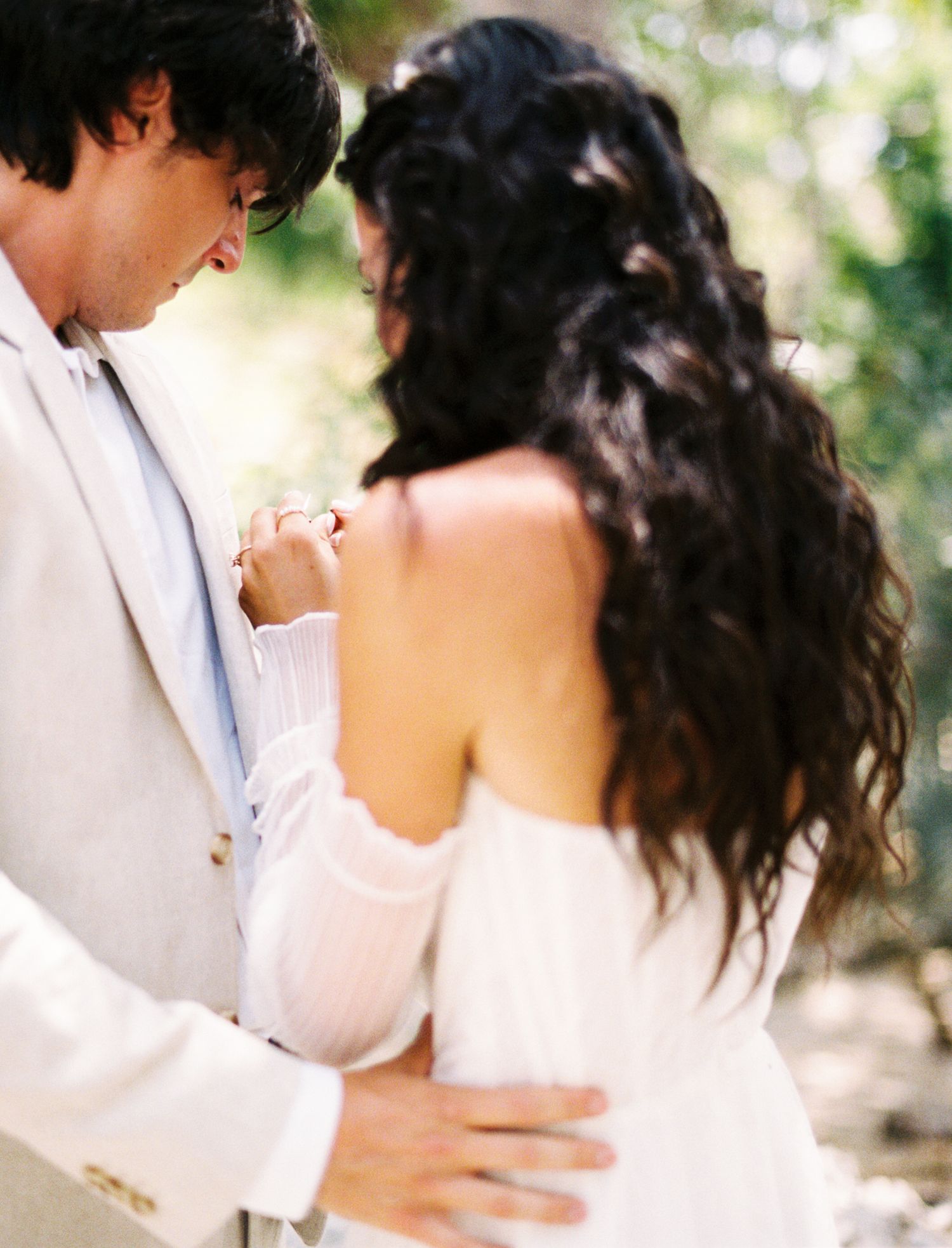 Romantic couple in white attire embracing outdoors with soft natural lighting and bokeh effect.